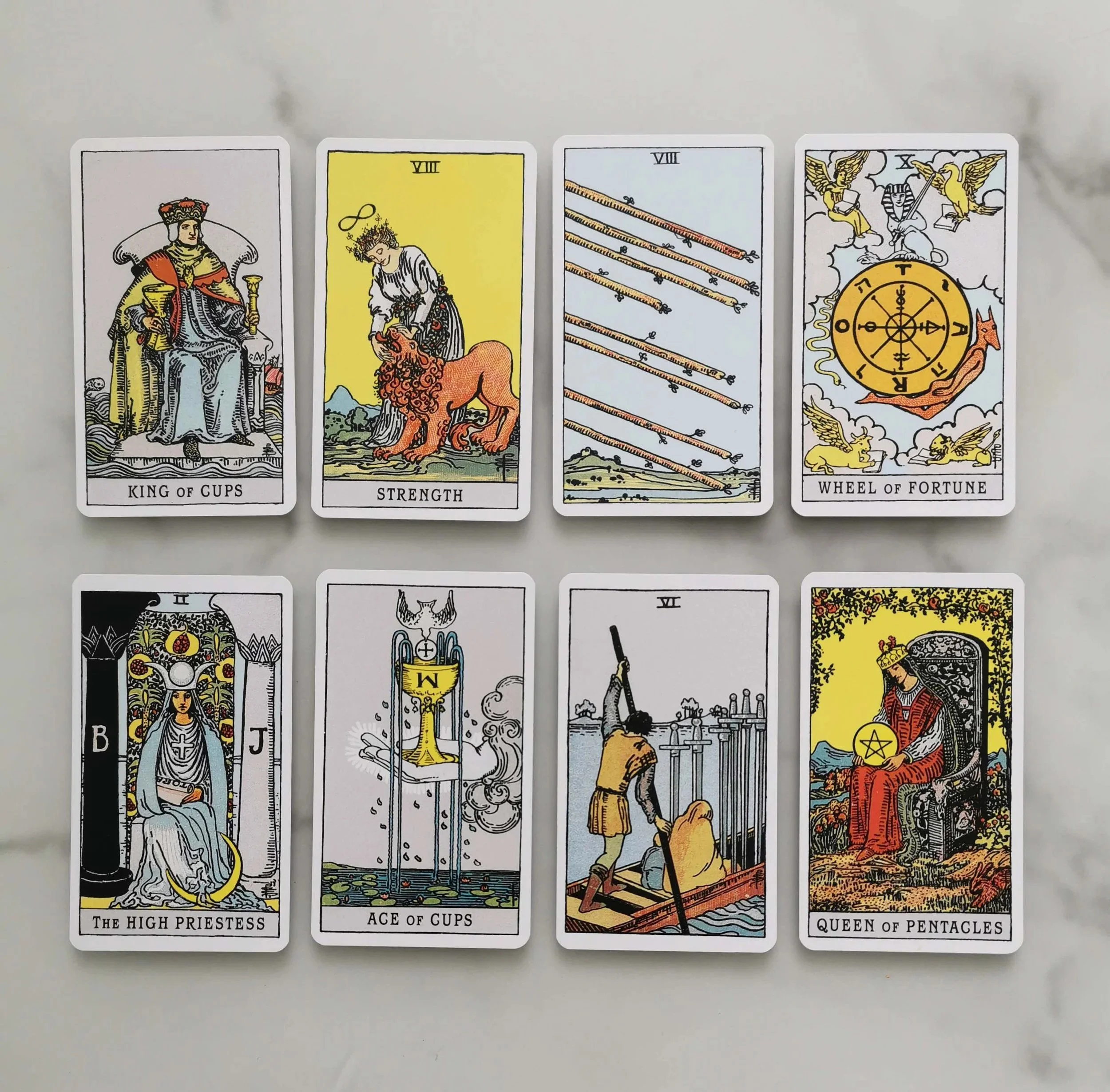 A layout of tarot cards including King of Cups, Strength, Eight of Wands, Wheel of Fortune, The High Priestess, Ace of Cups, Two of Swords, and Queen of Pentacles.