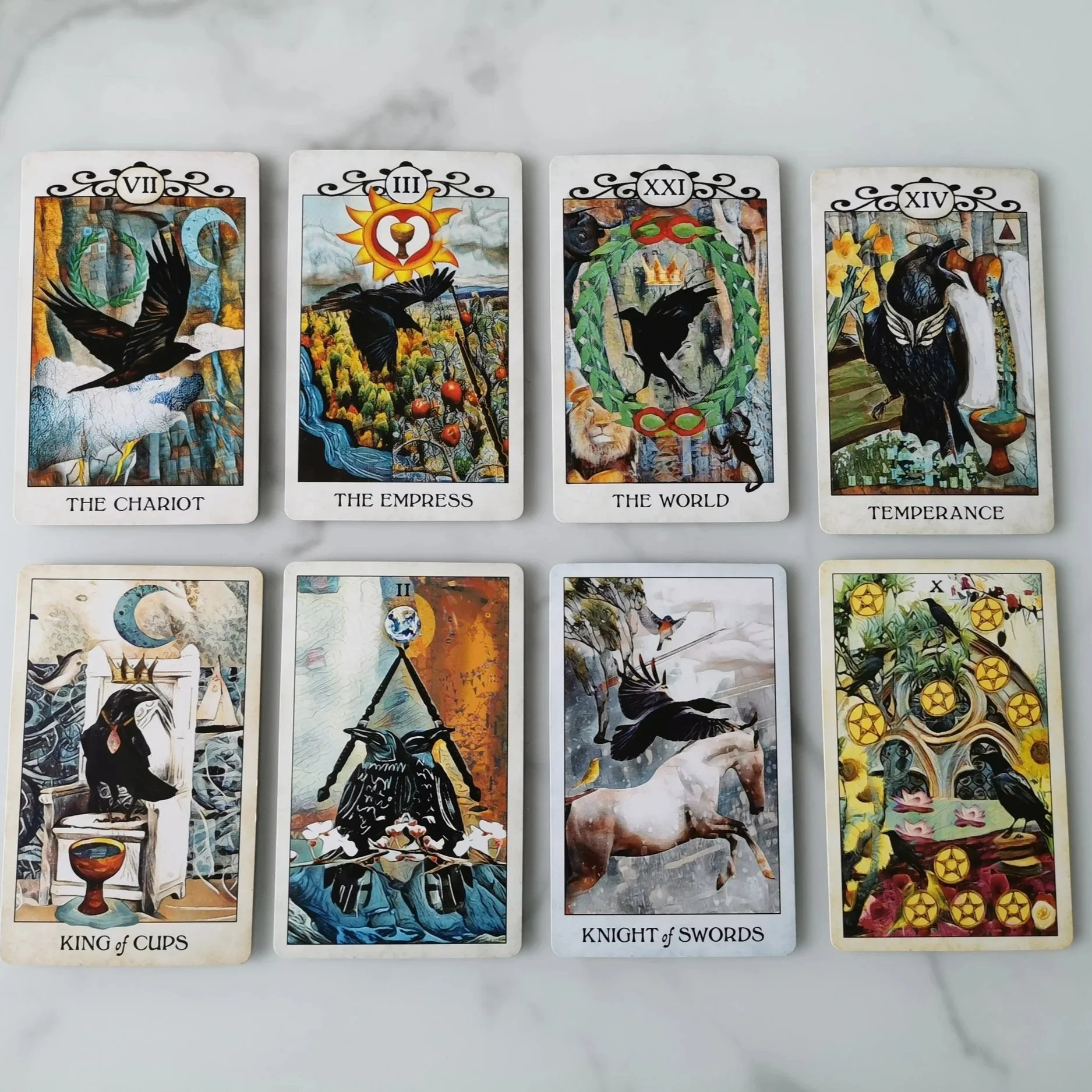 A collection of eight tarot cards arranged in two rows on a marble surface. The top row contains The Chariot, The Empress, The World, and Temperance. The bottom row contains King of Cups, Two of Swords, Knight of Swords, and Ten of Pentacles.