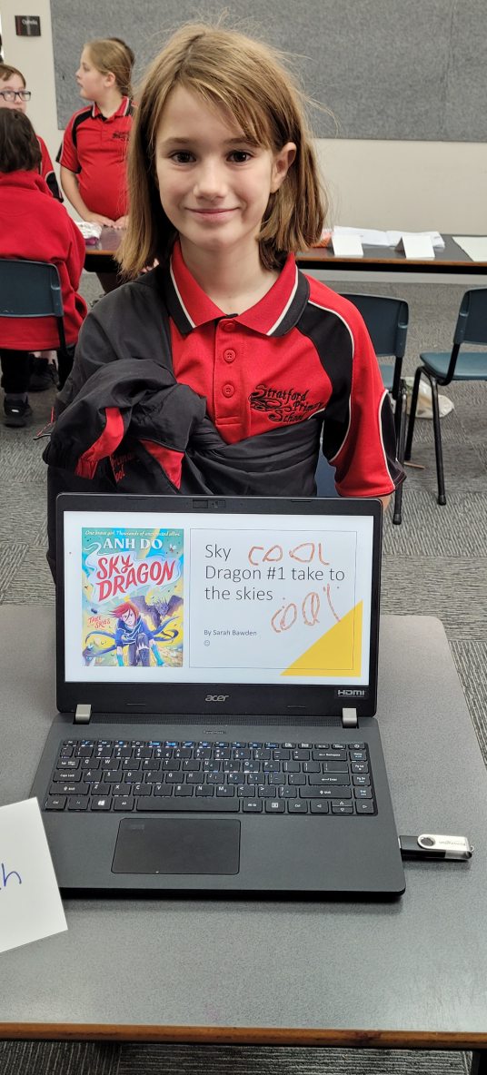 stratford student smiling behind a computer showing a games graphic