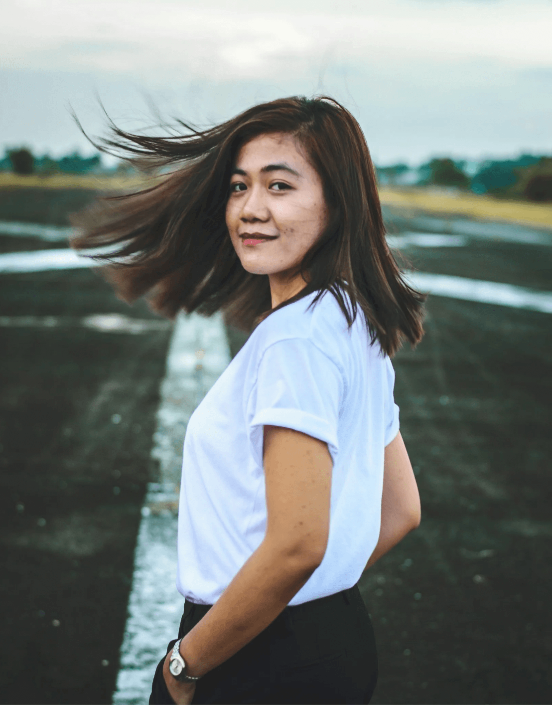 A woman with brown hair in a white shirt slightly smiling after body image therapy