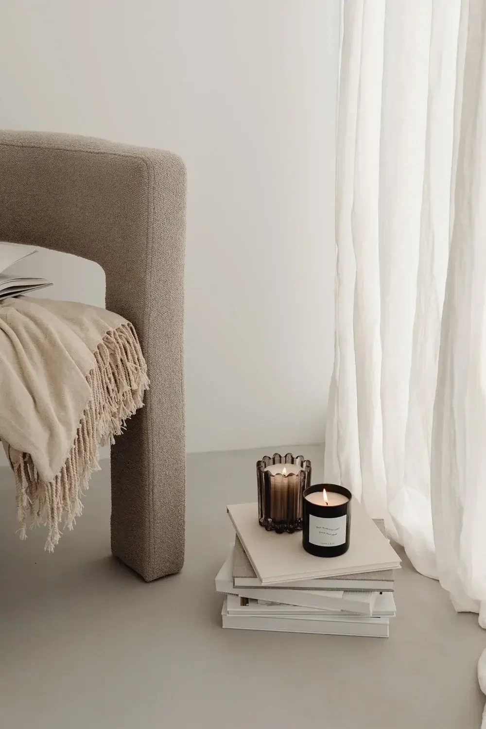 Beige chair with blanket draped across and candles on the floor