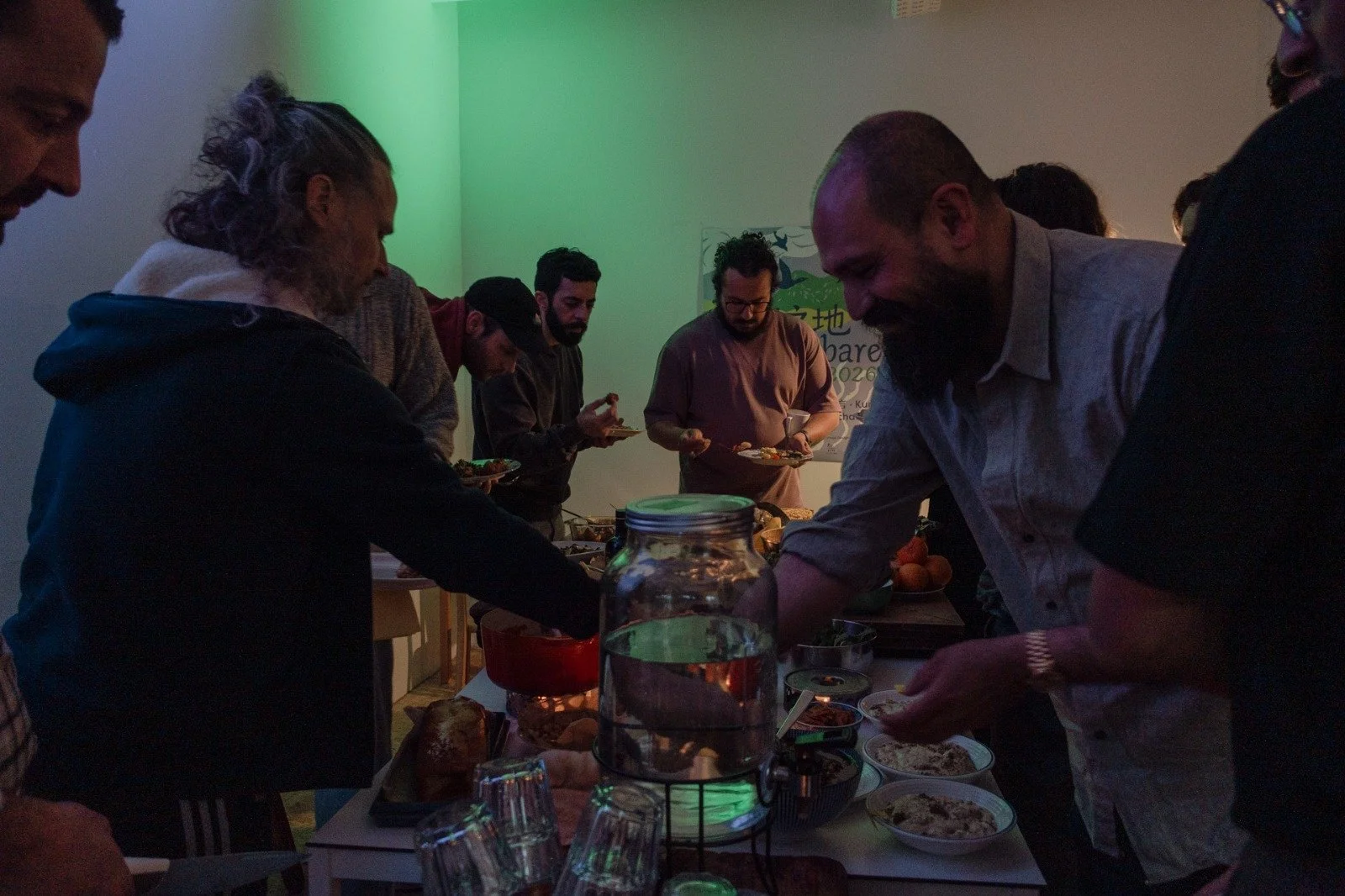People gathered around a table at a buffet, selecting food during an indoor event.