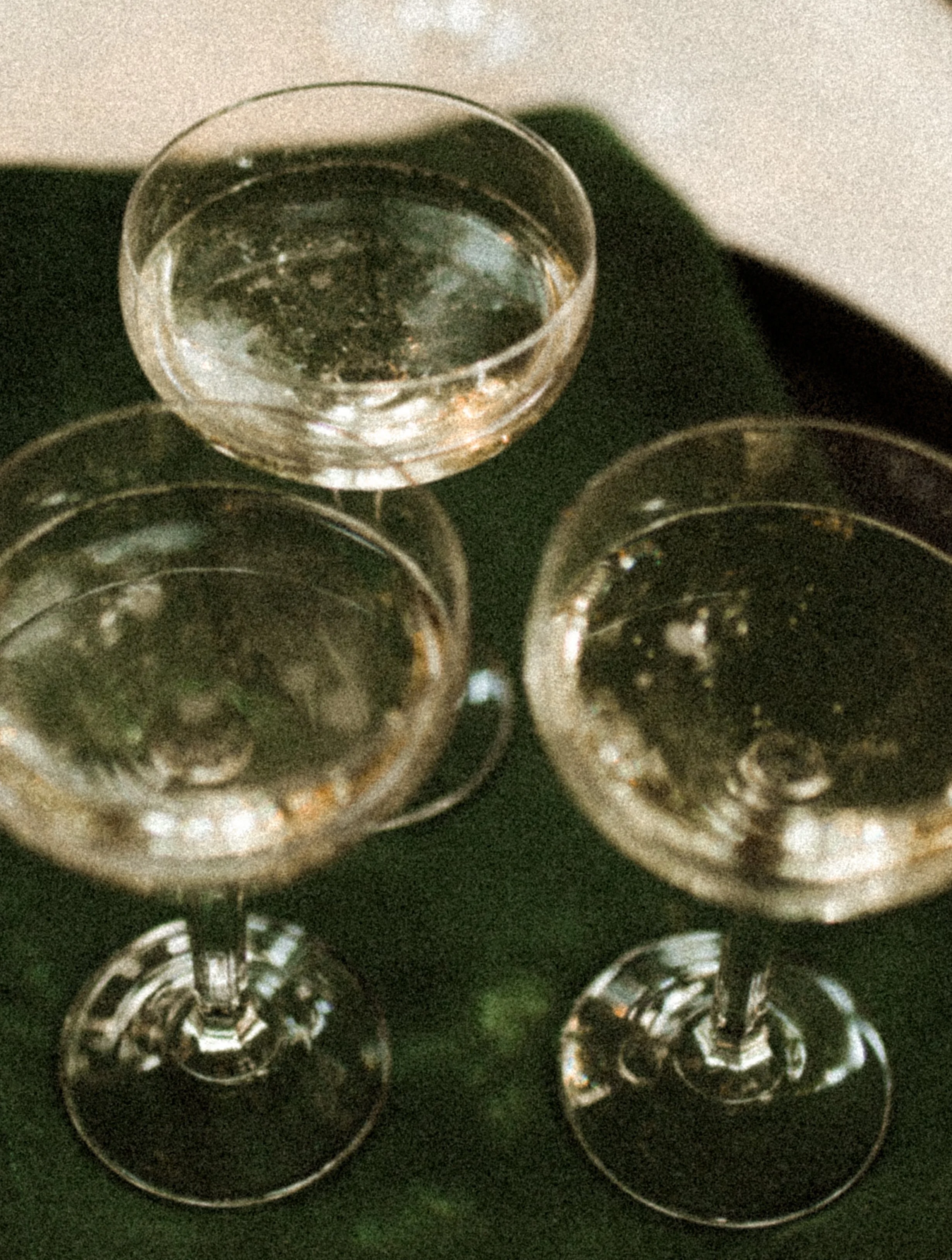 Three glasses filled with clear liquid, possibly water or champagne, viewed from above and placed on a dark surface.