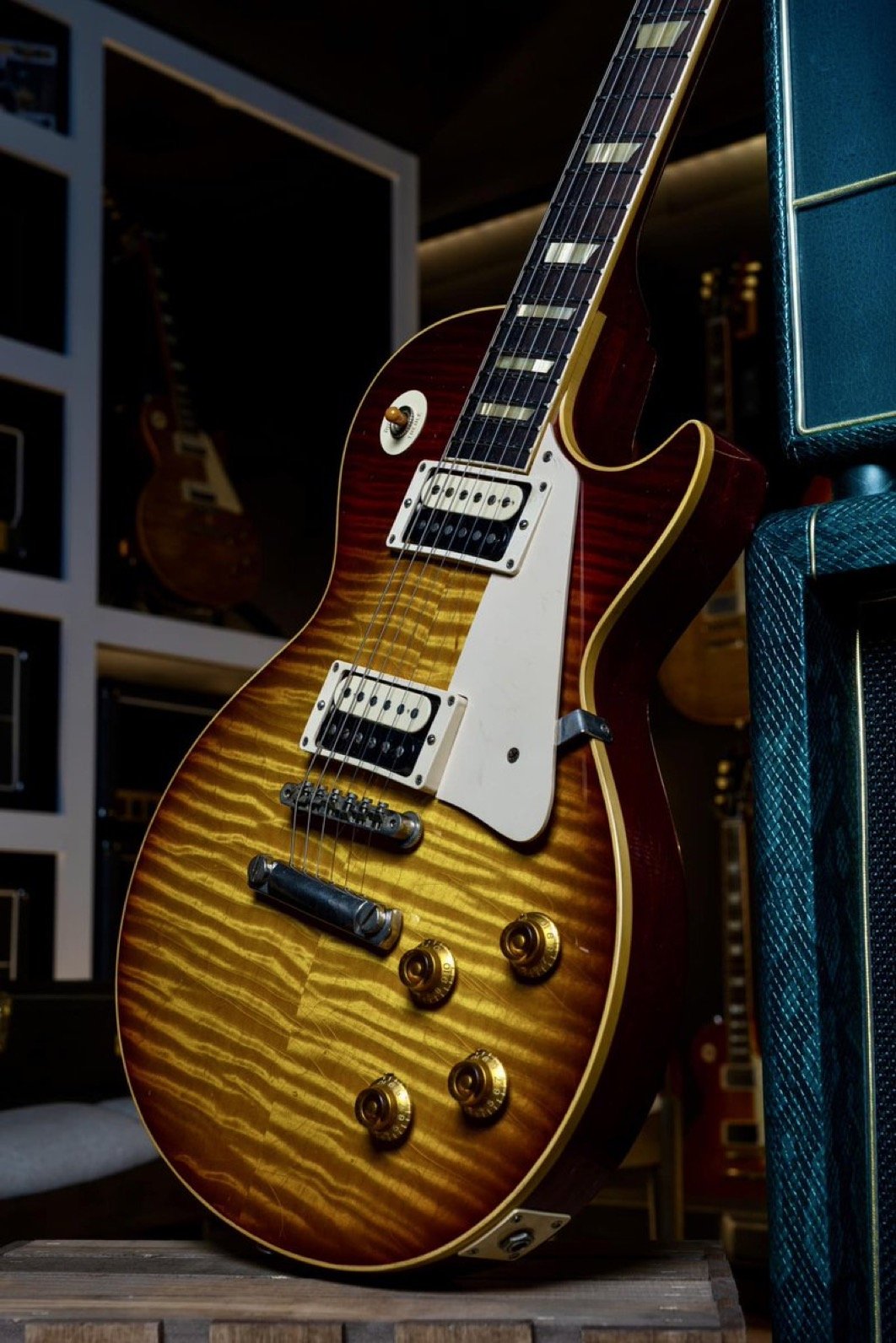 Electric guitar with sunburst finish displayed near a speaker in a music store.