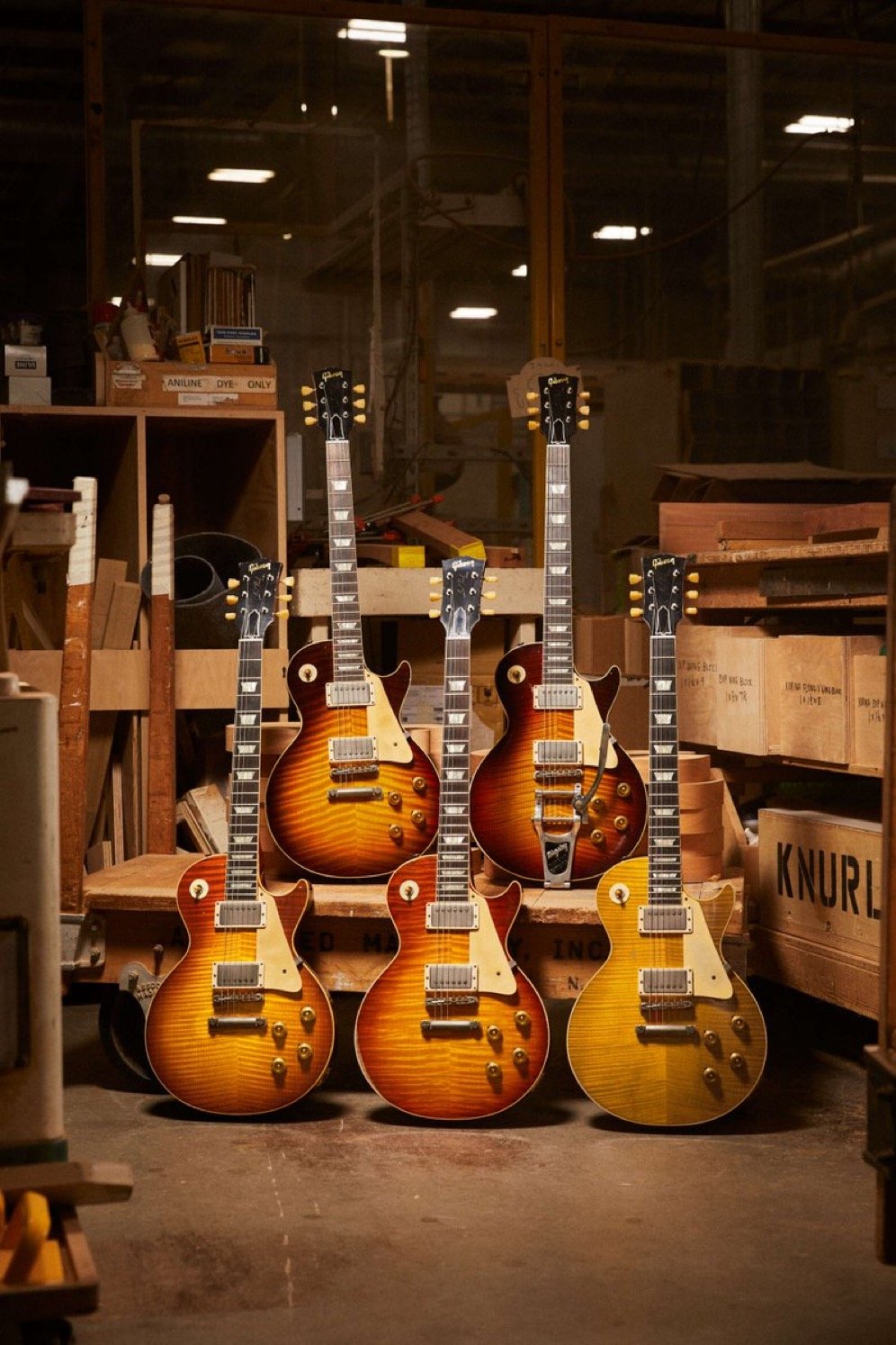 Five electric guitars with sunburst finishes displayed in a workshop setting.