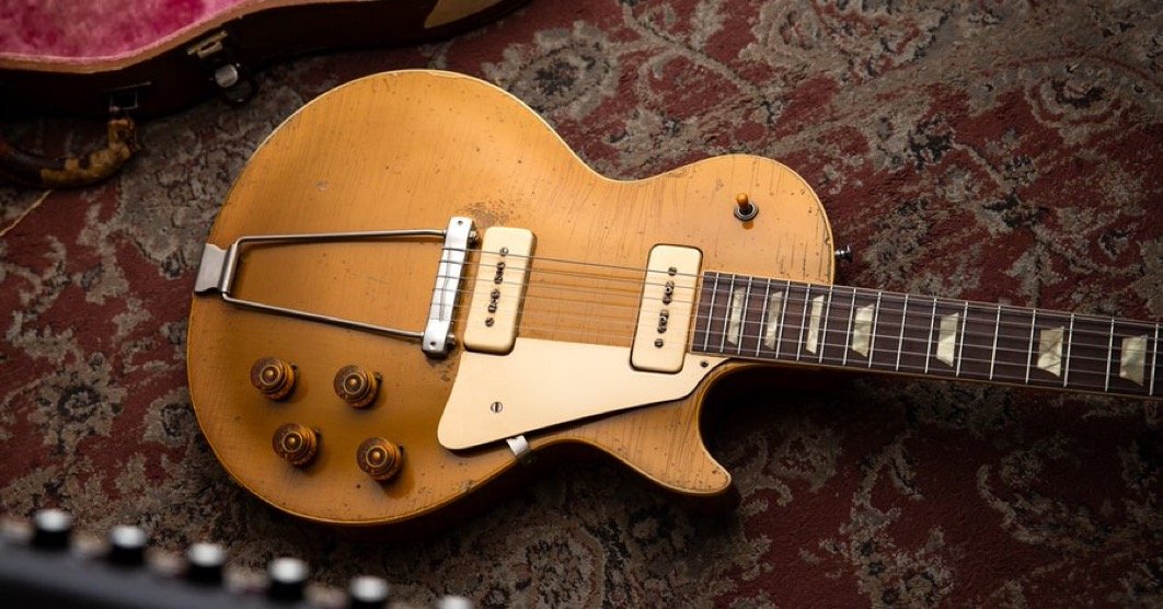 Vintage gold electric guitar with P-90 pickups on a patterned rug.