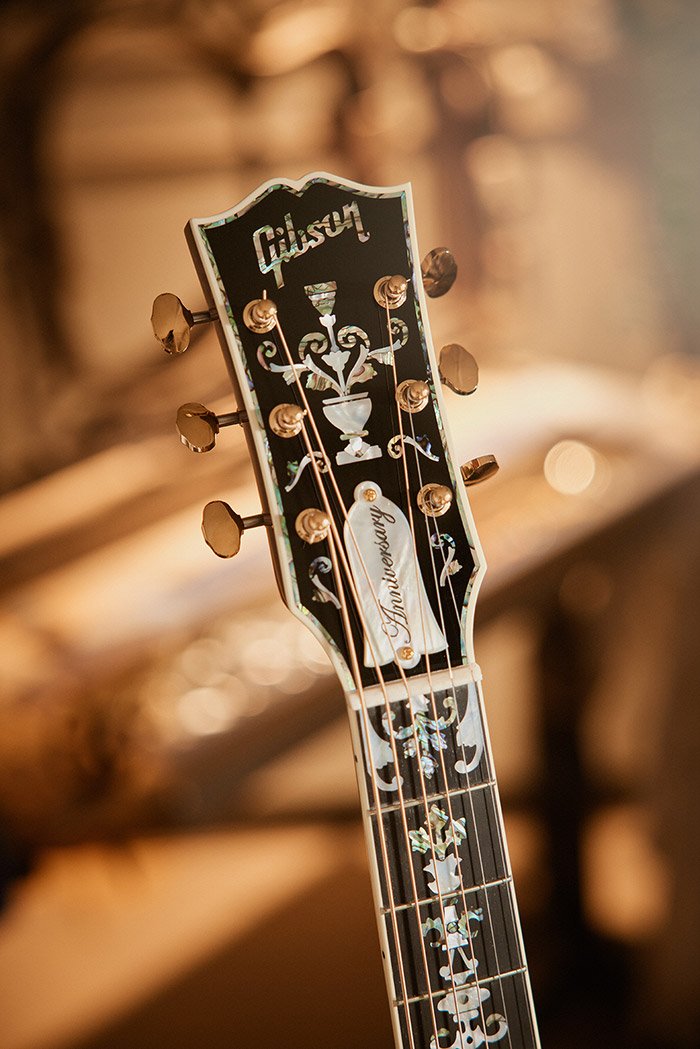 Guitar headstock with intricate inlay design and brand logo.