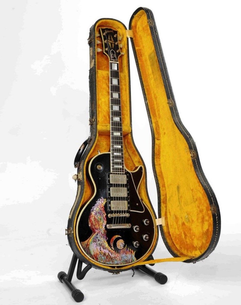Electric guitar in open vintage case, featuring colorful abstract artwork on the body, with black finish and multiple knobs.