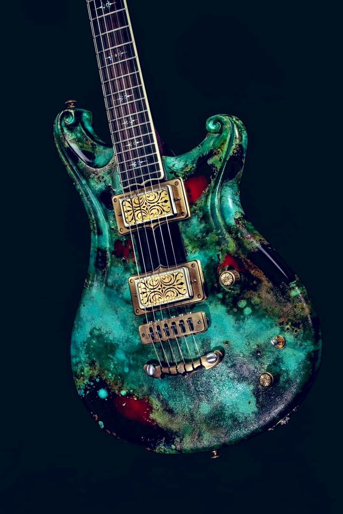 A turquoise electric guitar with ornate pickups and a unique, textured finish.