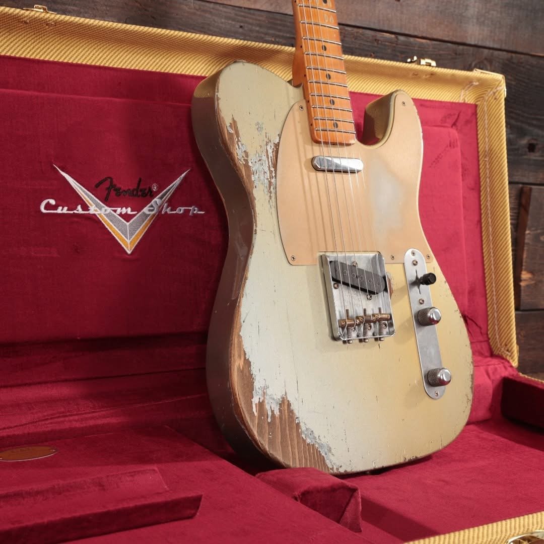 Vintage Fender electric guitar in a red velvet-lined case with 'Fender Custom Shop' logo, featuring a worn, aged finish on the body.