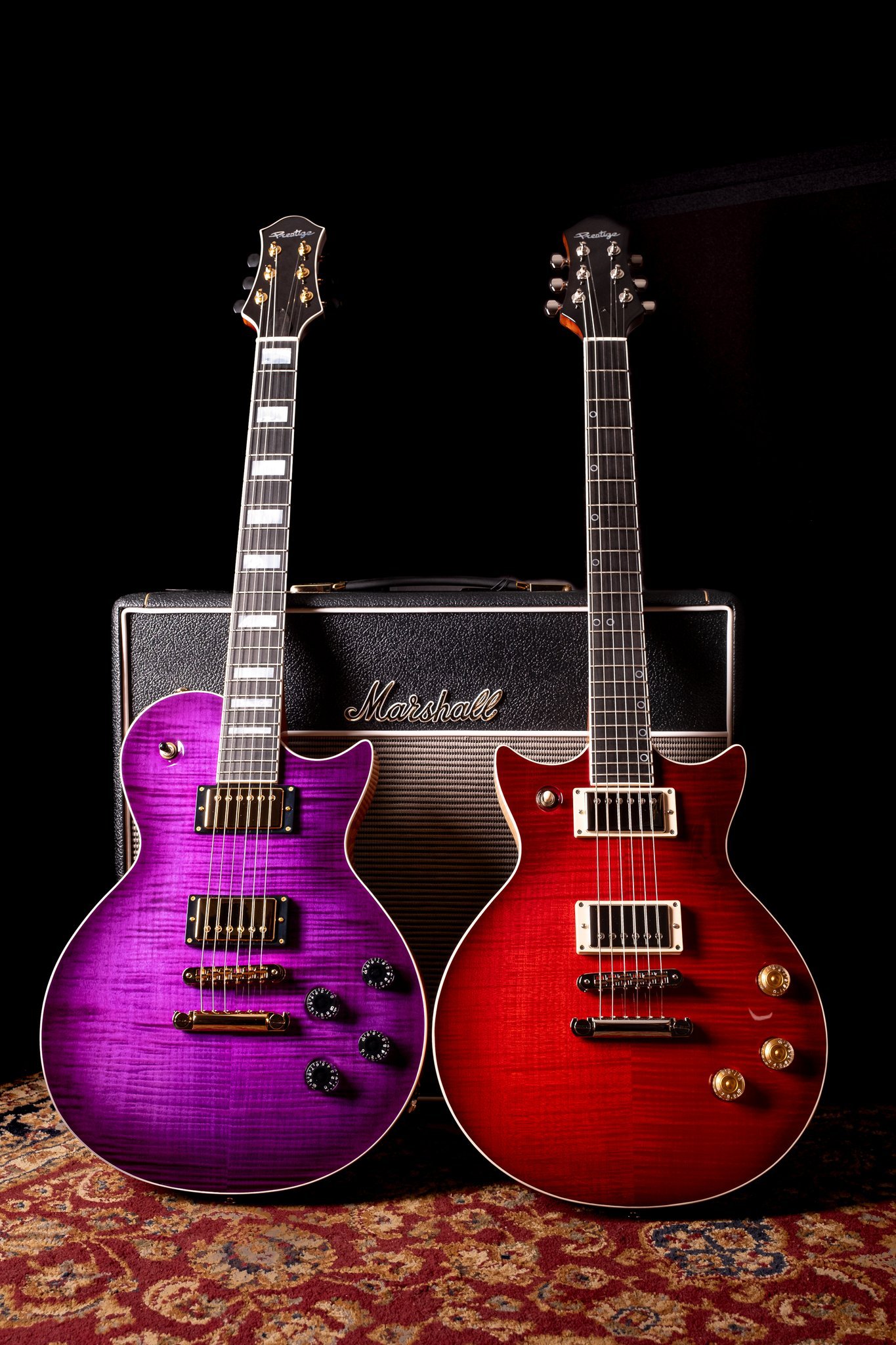 Two electric guitars, one purple and one red, standing in front of a Marshall amplifier on a decorative rug.