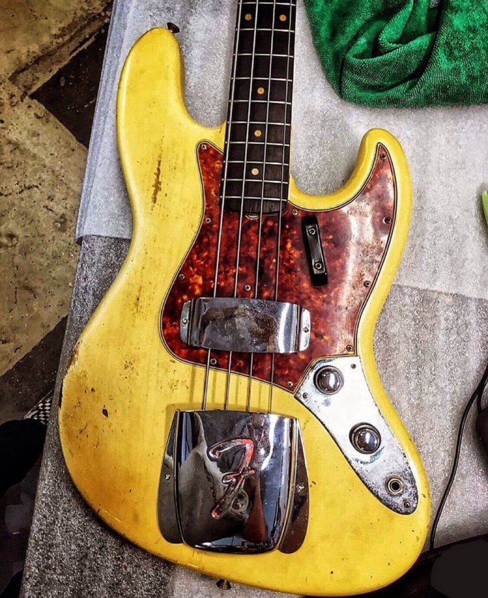 Vintage electric bass guitar with yellow body and tortoiseshell pickguard on a table.