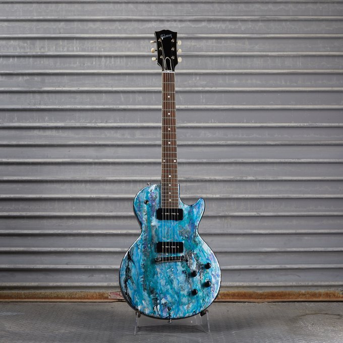 Blue electric guitar with textured finish against gray metal background
