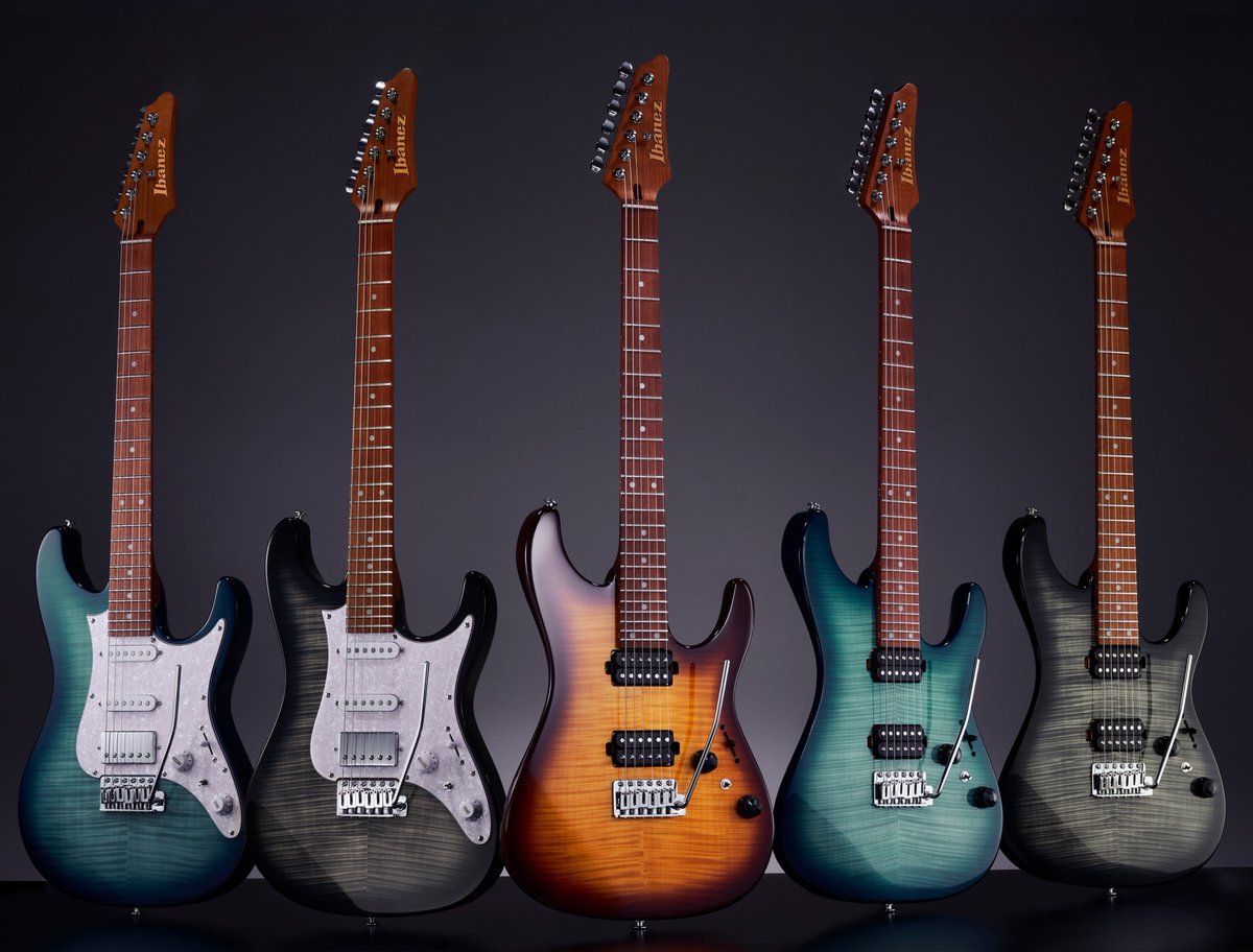 Five electric guitars arranged side by side against a dark background, showcasing various color finishes and models.