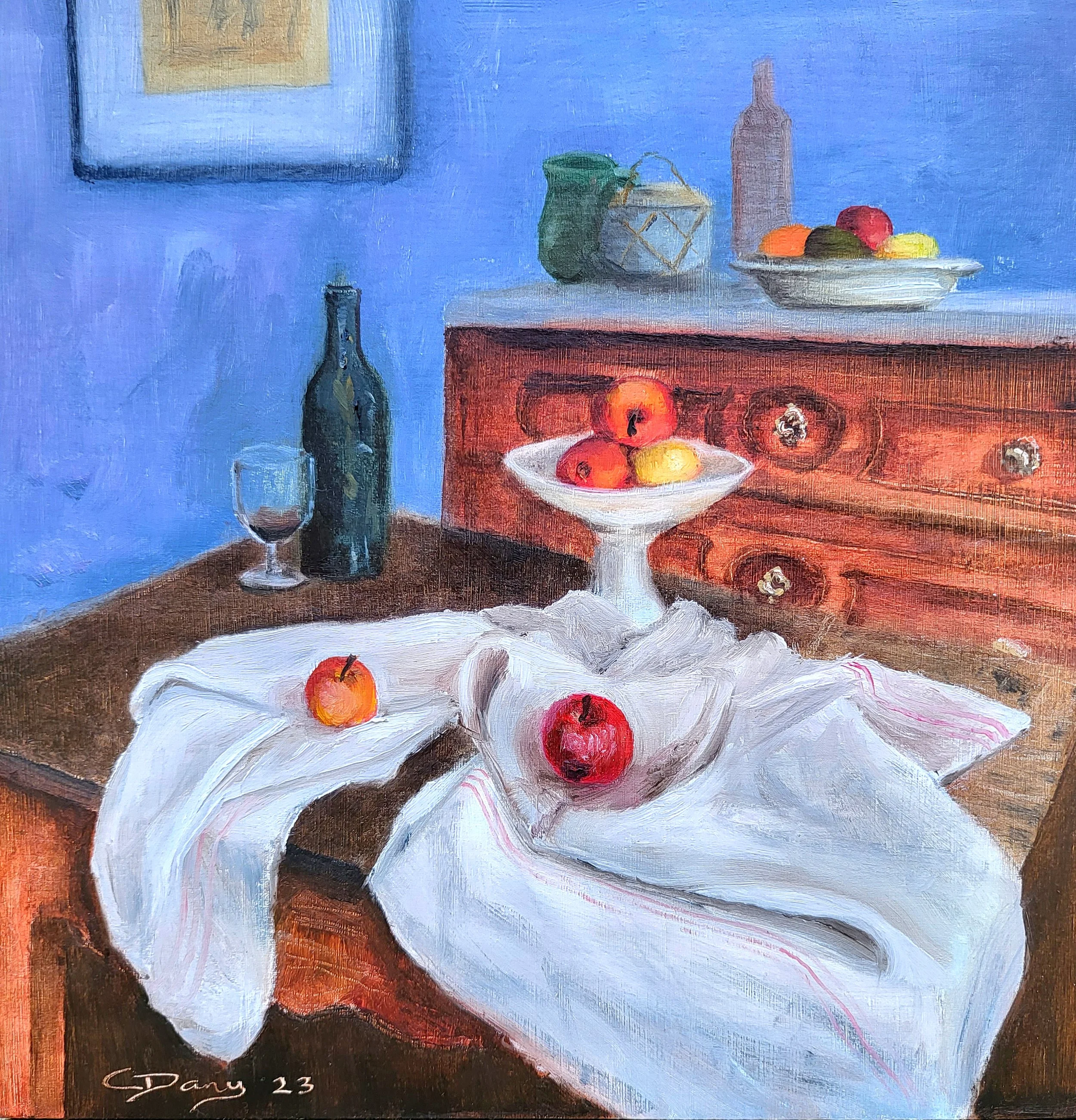 Still life painting with apples on a white cloth, a pedestal bowl with fruit, a wine bottle, and a glass on a wooden table against a blue wall.