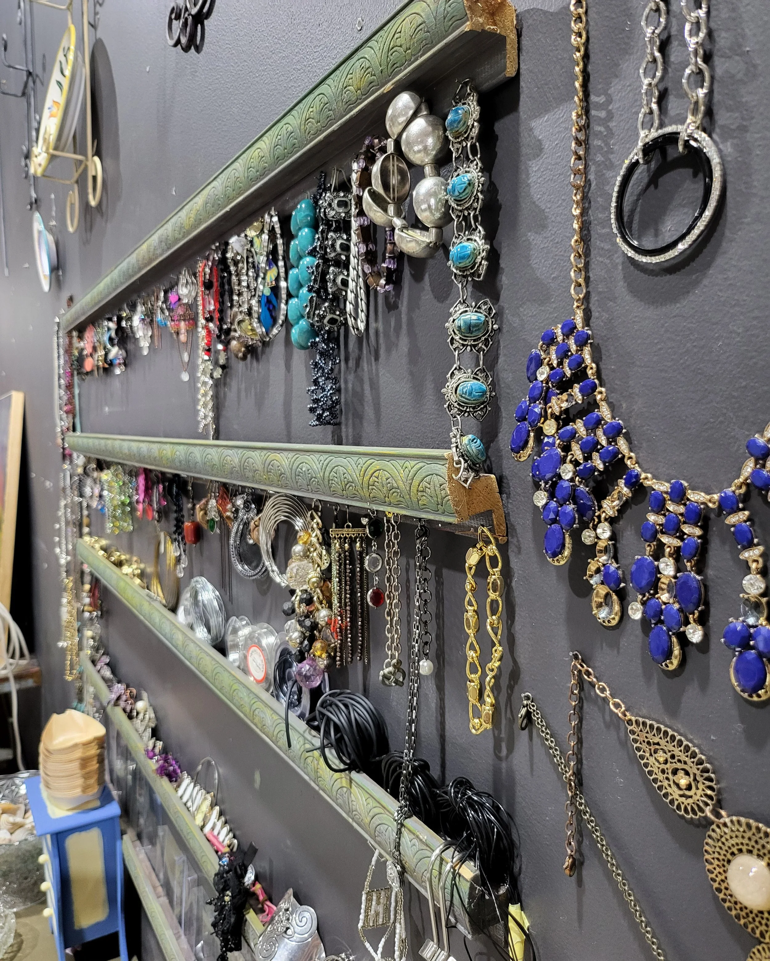 Wall-mounted jewelry display with various necklaces, bracelets, and accessories in a store.
