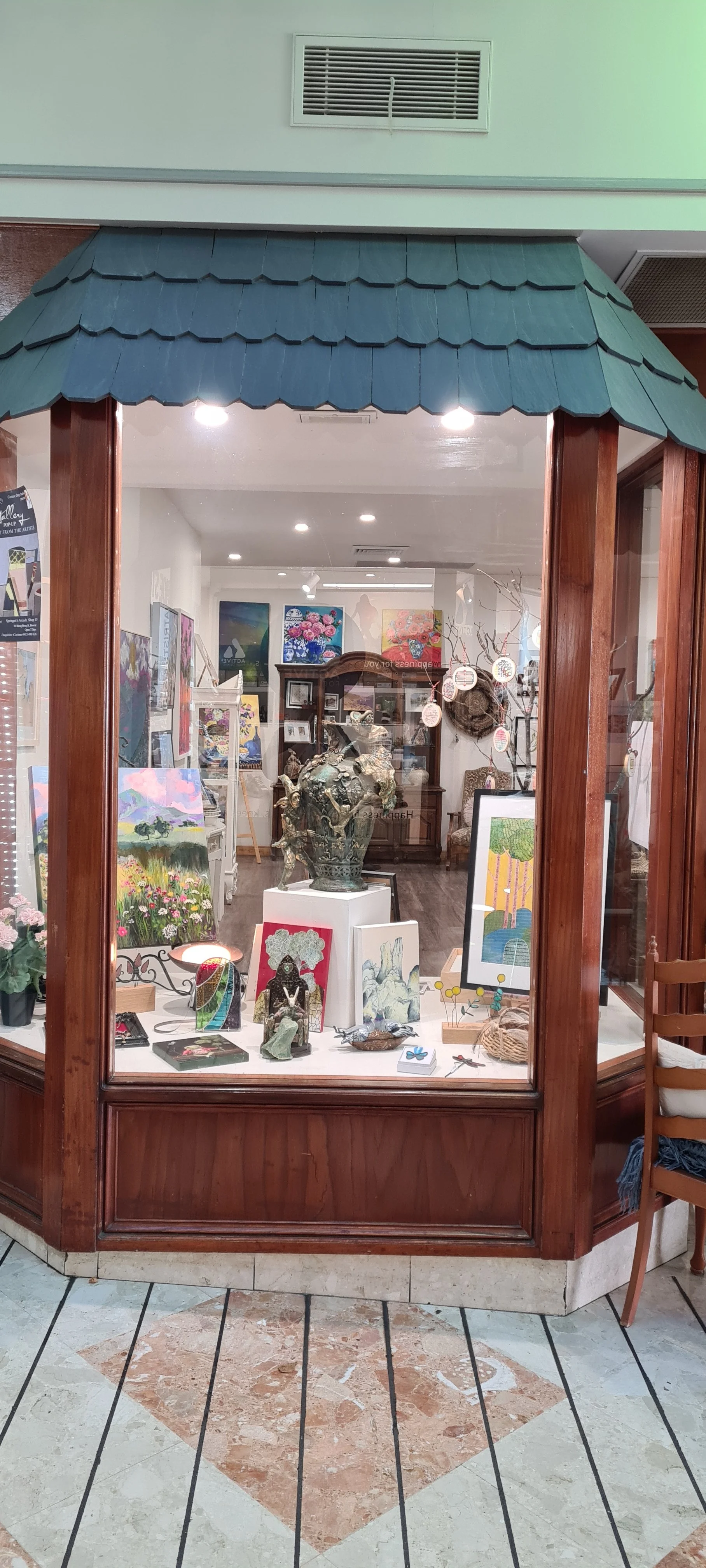 Decorative wall featuring a painting of a deer in a white ornate frame, a rabbit sculpture in colorful clothing, and flowers with leafy vines.