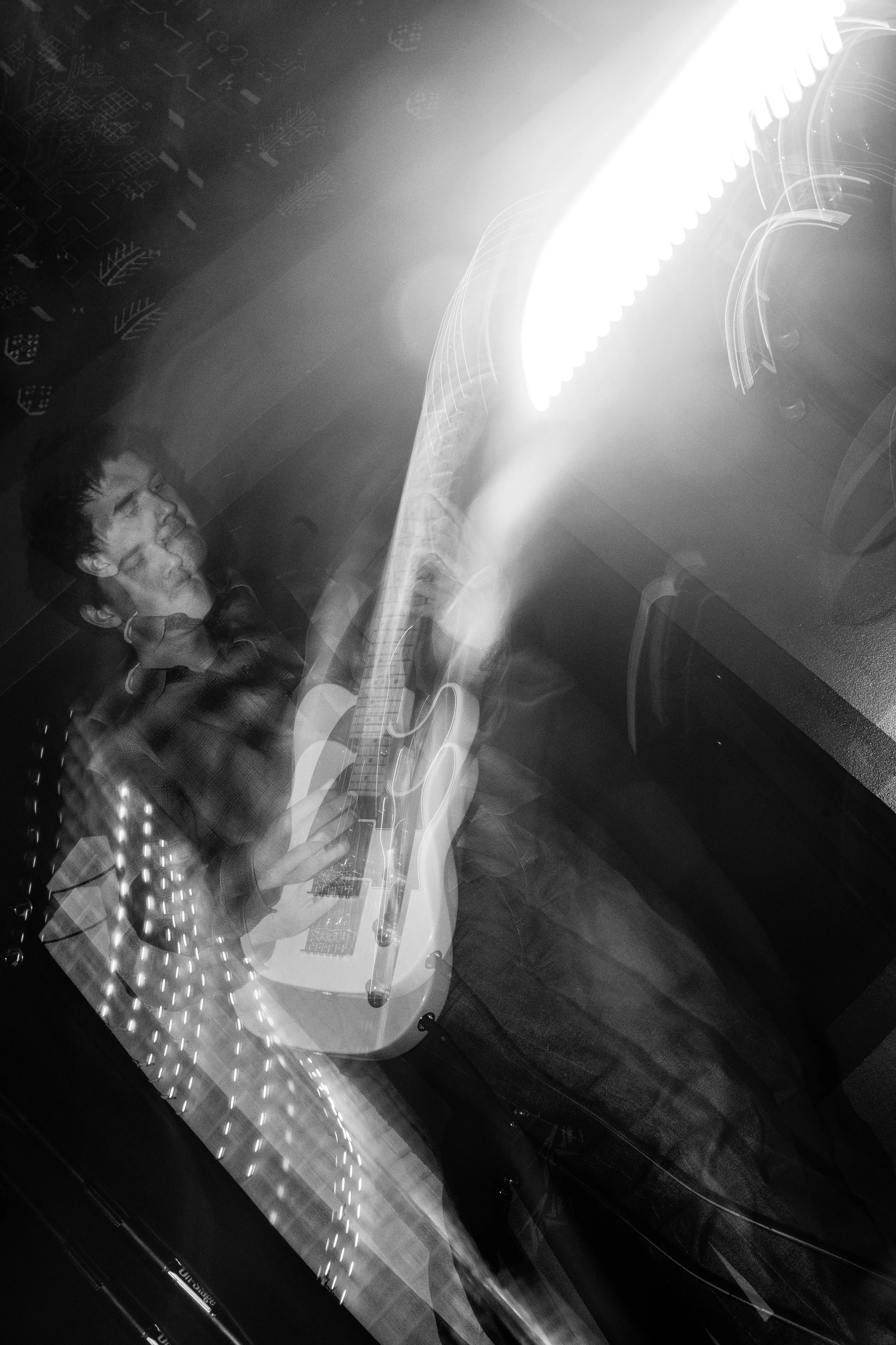 A person playing an acoustic guitar in a dimly lit room, with light streaks and motion blur creating a dynamic, energetic atmosphere.
