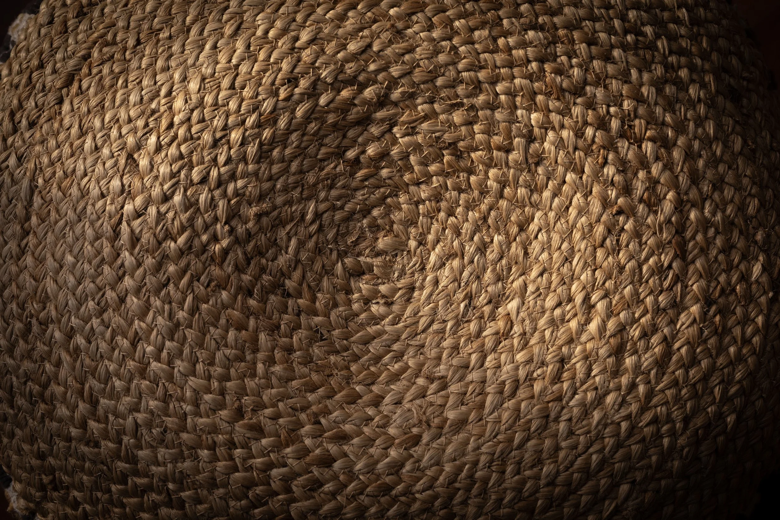 Close-up of woven straw or rattan material, showing detailed texture and pattern.
