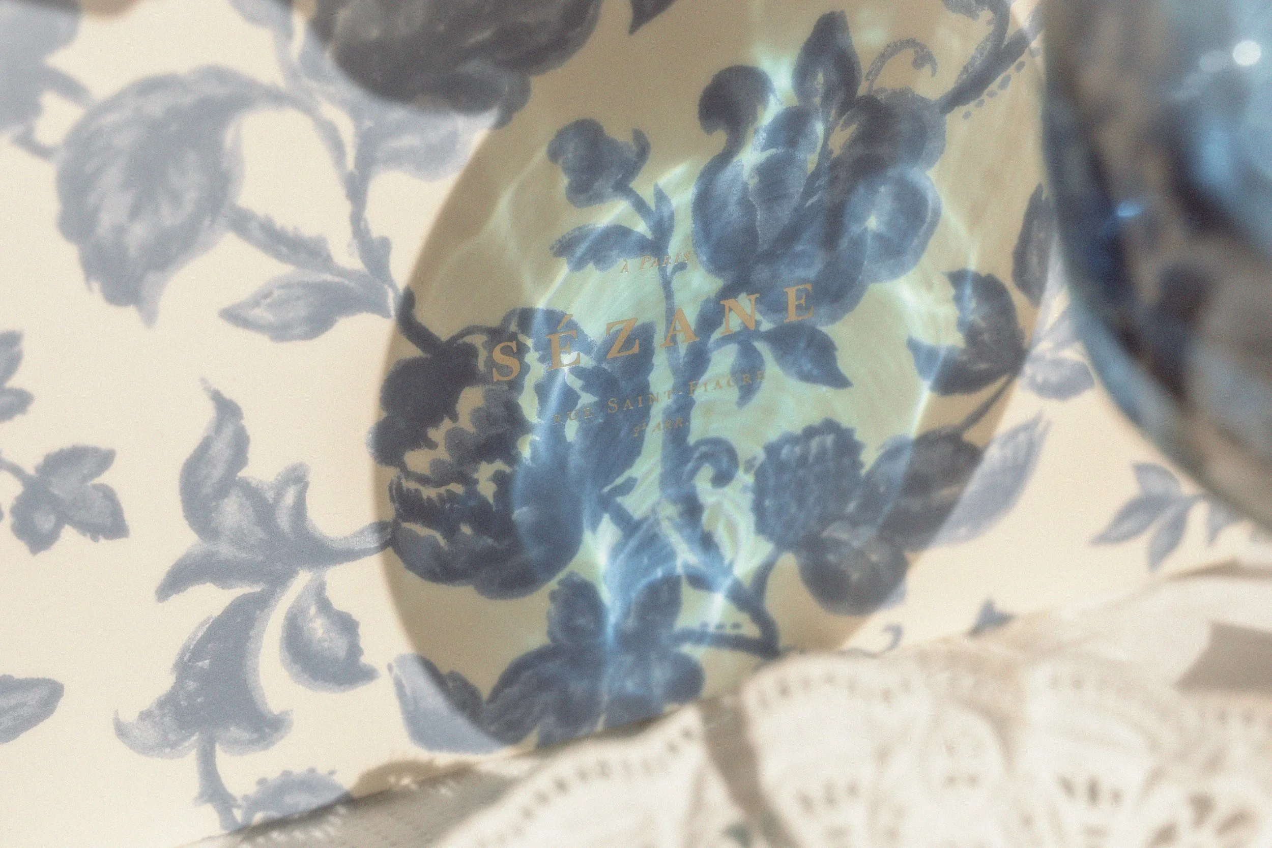 Close-up of a paper bag with a floral pattern and gold foil text that reads 'Sézane' and 'A Paris'.