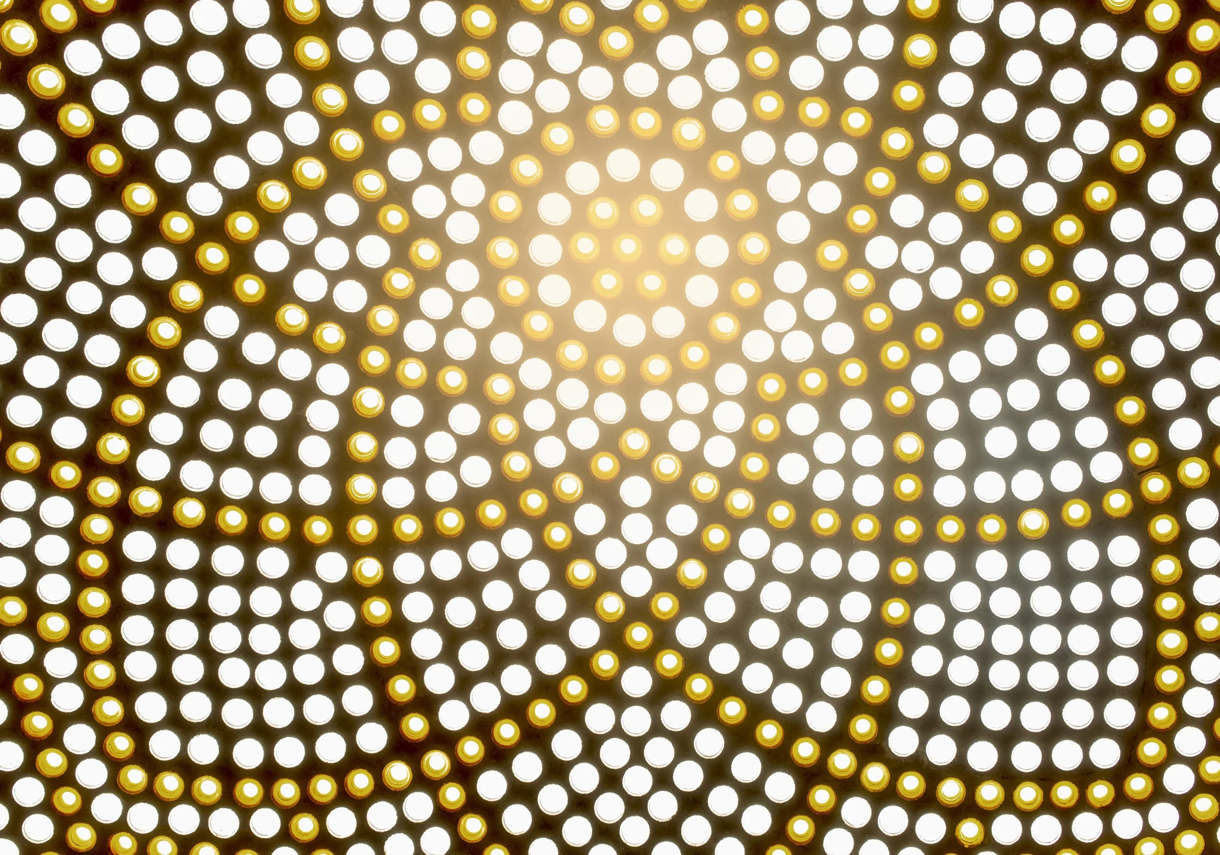 Close-up of illuminated circular dots, yellow and white, with a bright light in the center creating a glowing effect.