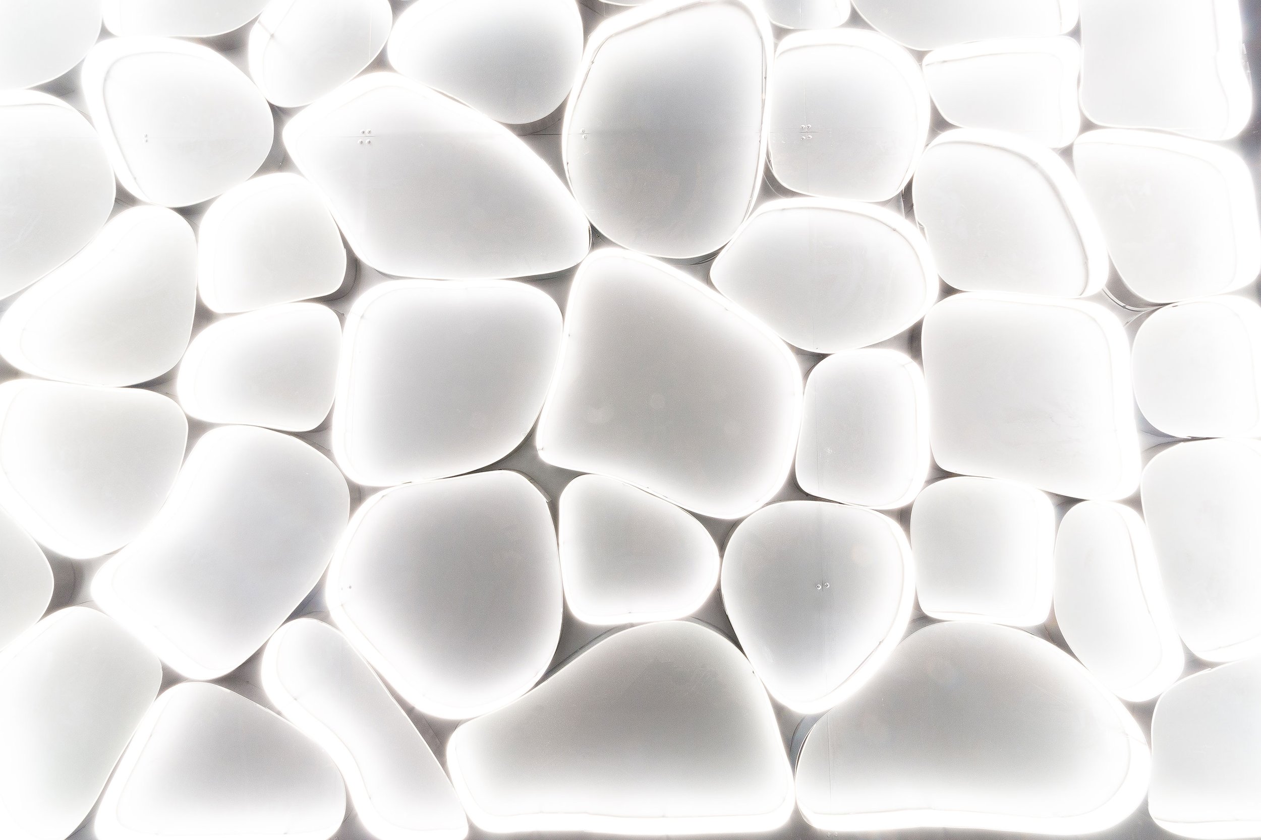 Close-up of glowing white, rounded, pebble-shaped objects arranged closely together.