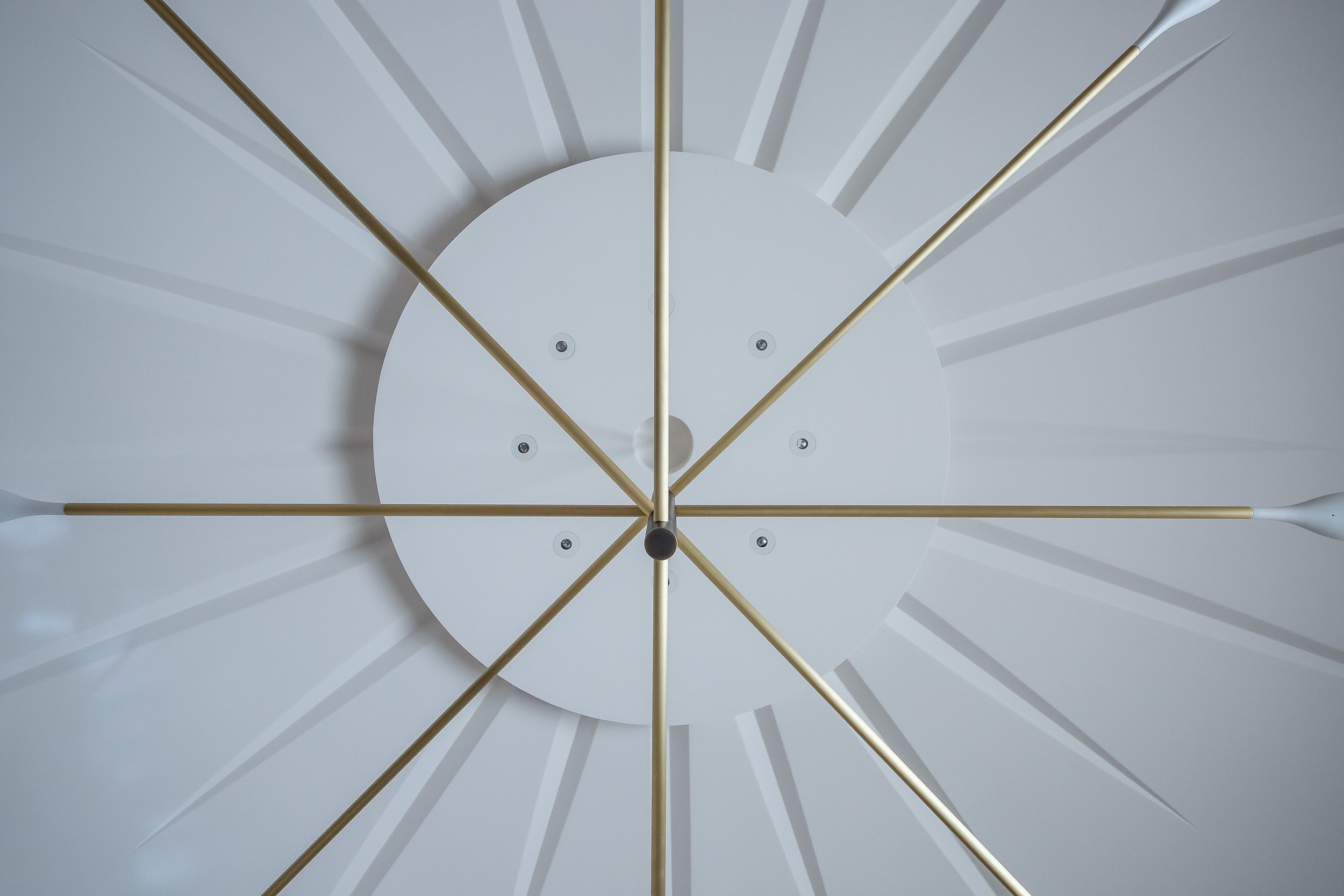 Close-up of a modern wall clock with gold-colored hands and minimalistic design, showing the time as approximately 12:12.
