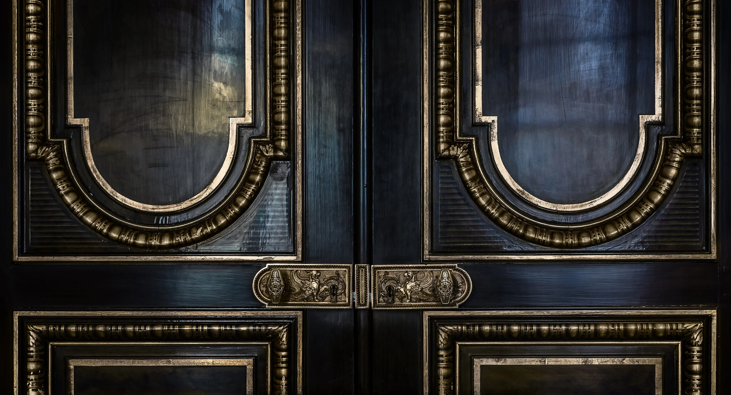 Decorative black and gold double doors with ornate gold trim and lion motifs on the handles.