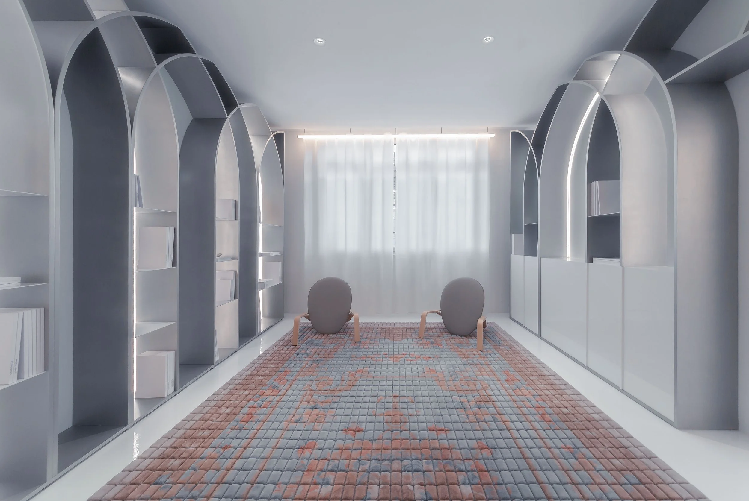 Modern room with built-in bookshelves on both sides, a colorful woven rug, and two modern chairs facing away from the window with sheer curtains and ceiling lights.