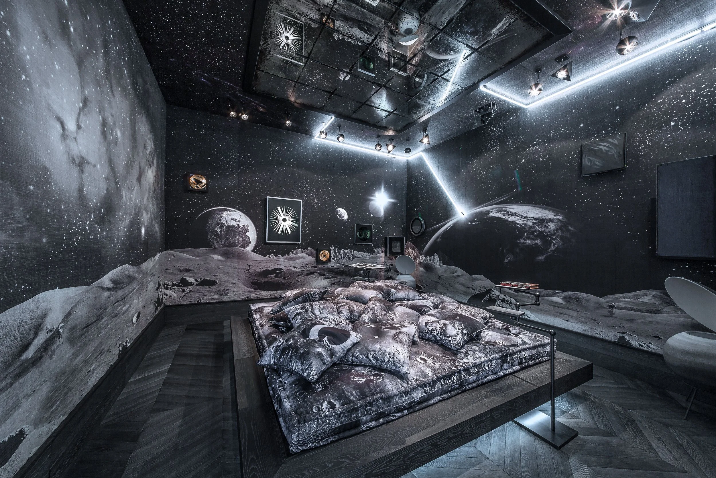 A space-themed bedroom mural depicting planets, stars, and the moon on the walls and ceiling, with moon surface bedding on the bed.