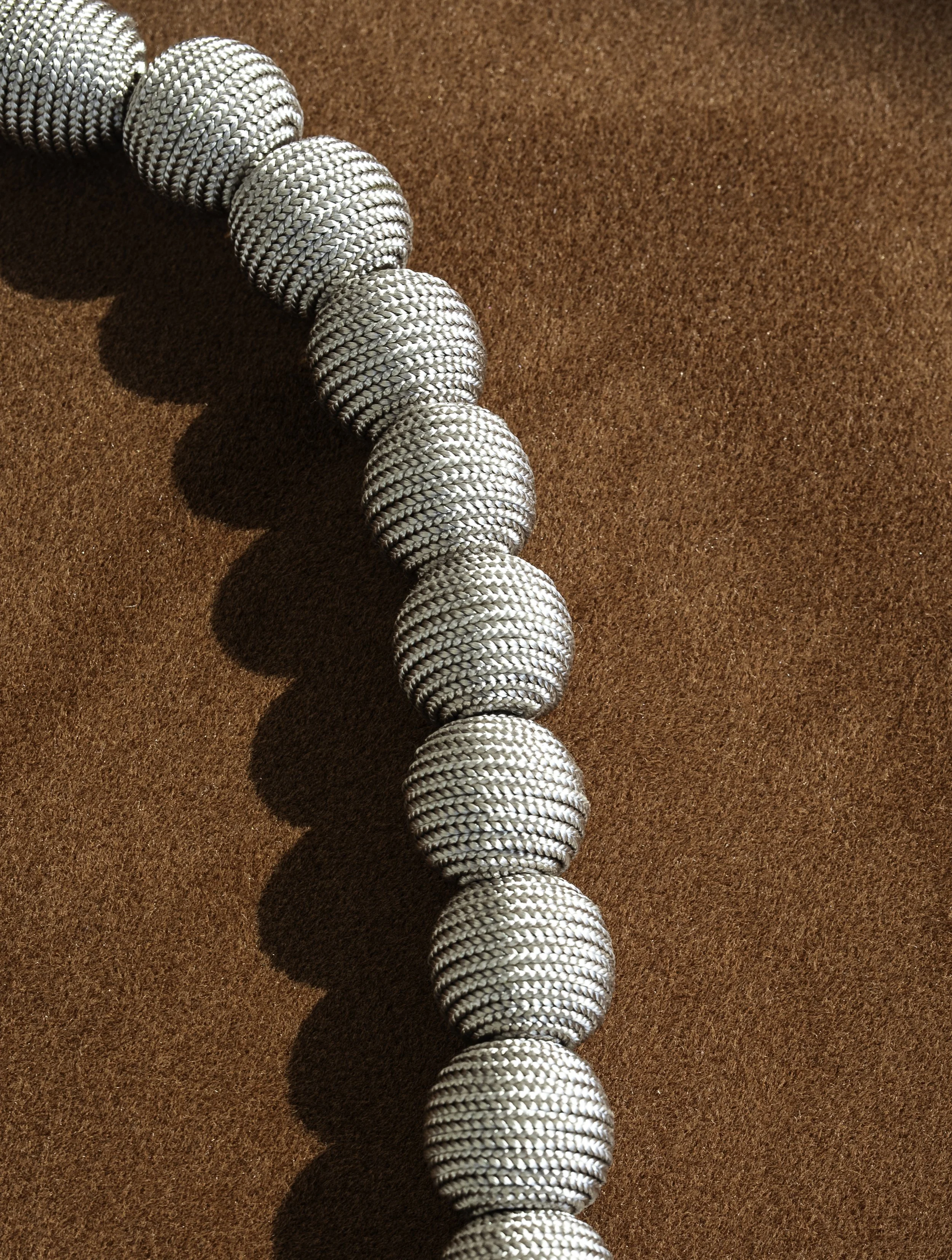 A line of silver metallic weights on an orange textured surface.