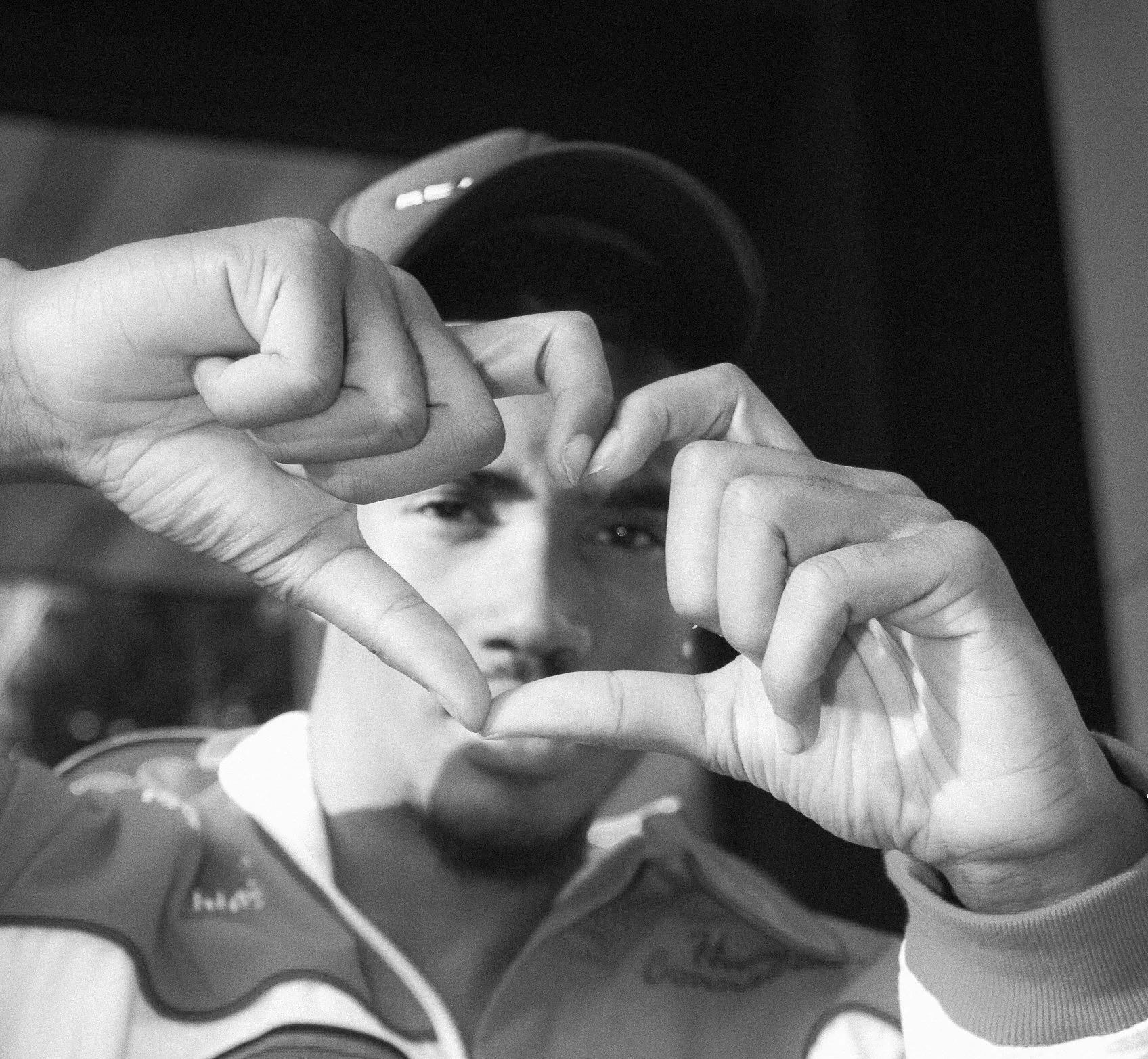Black and white photo of a person forming a heart shape with their hands.