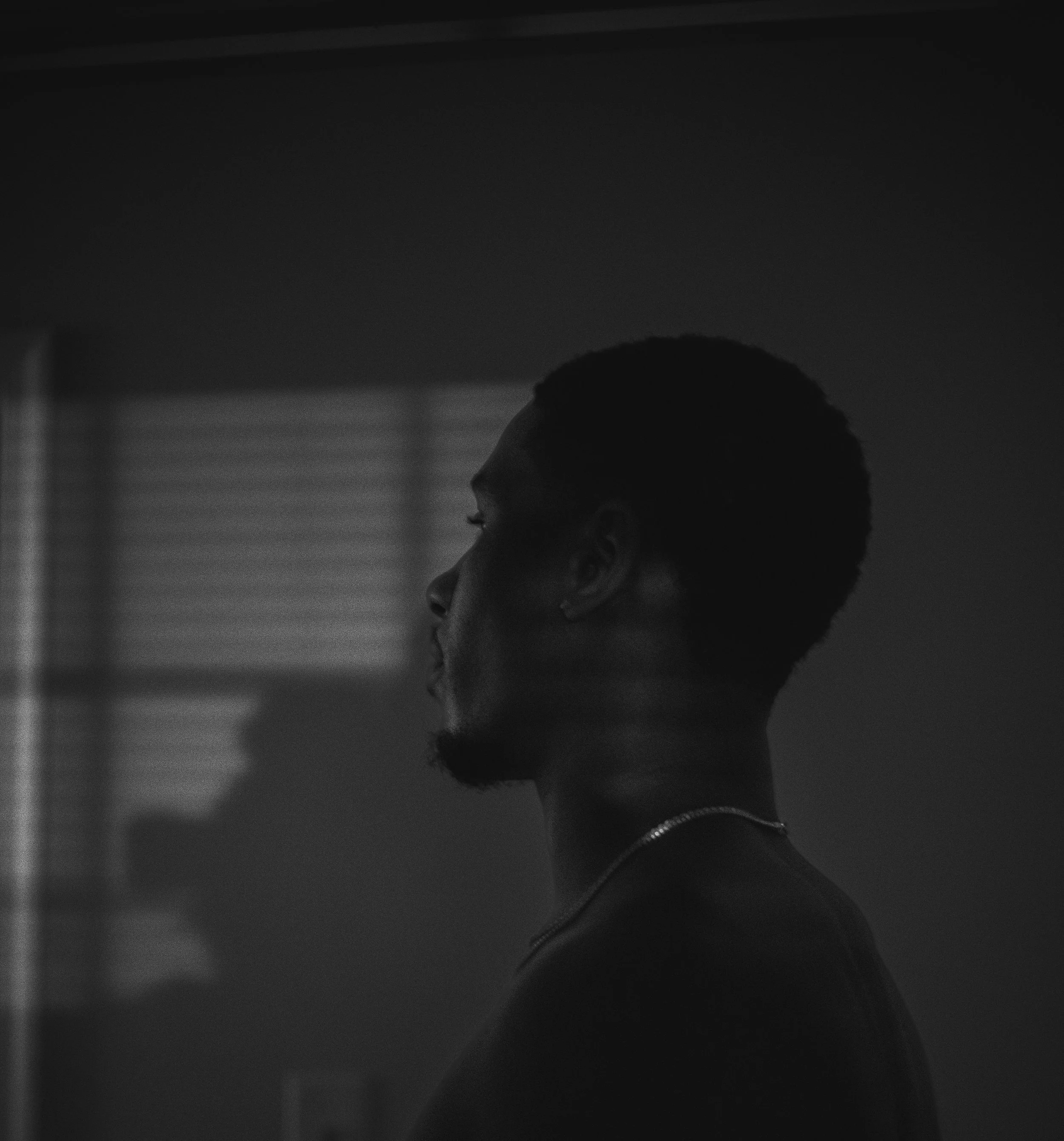 Silhouette of a man in profile against a background with window light shadows.