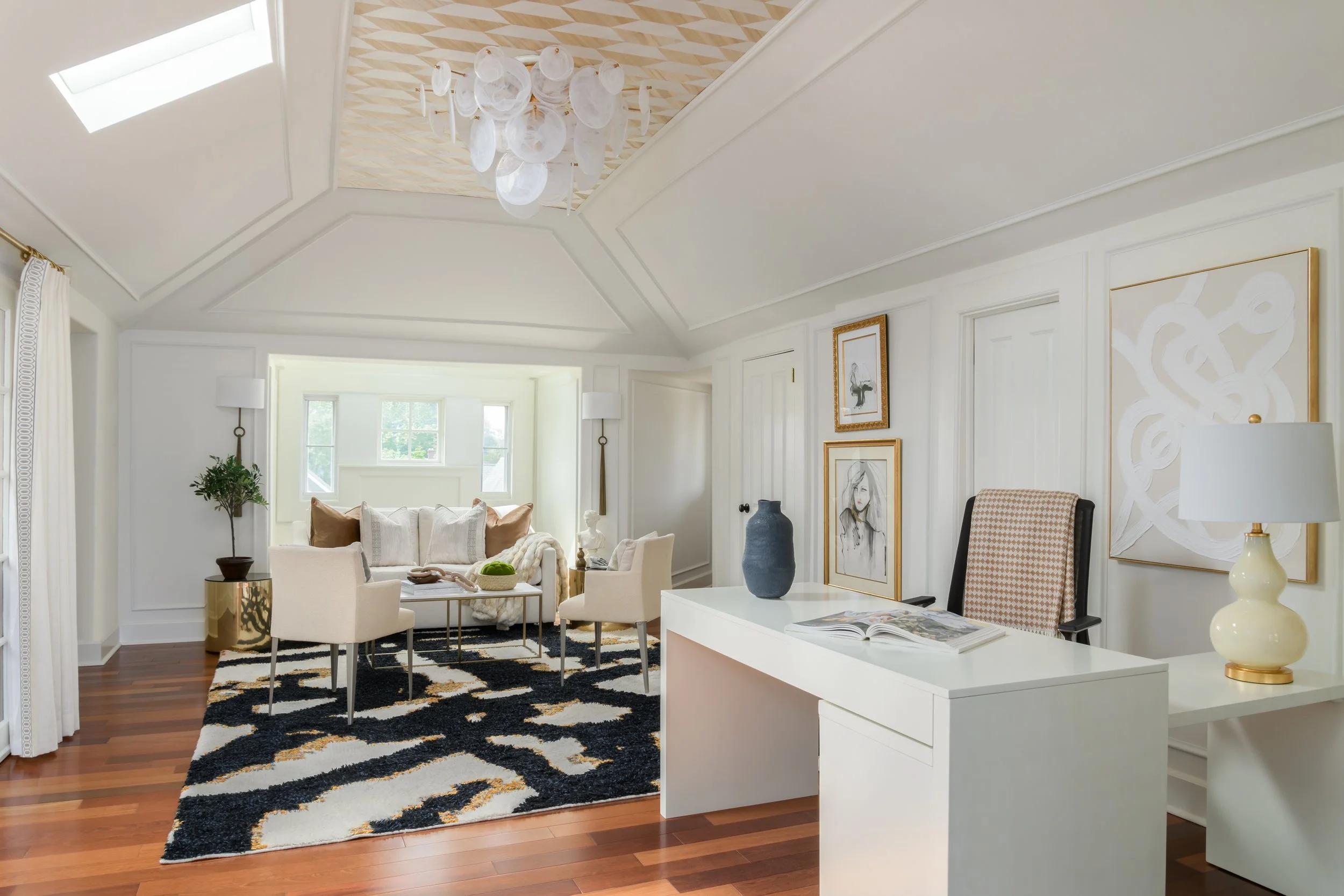 Living room with white walls, a large window, and modern decor including artwork, vases, and a black and white patterned rug.