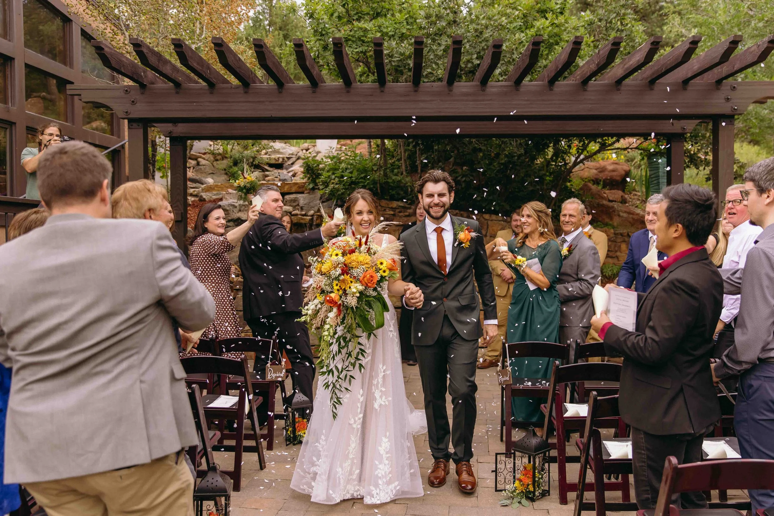 A colorado wedding couple walks back down the aisle after just getting married, with dried flowers thrown and big smiles on their faces. late summer Colorado wedding at craftwood peak with fun vendors and beautiful florals surrounded by love