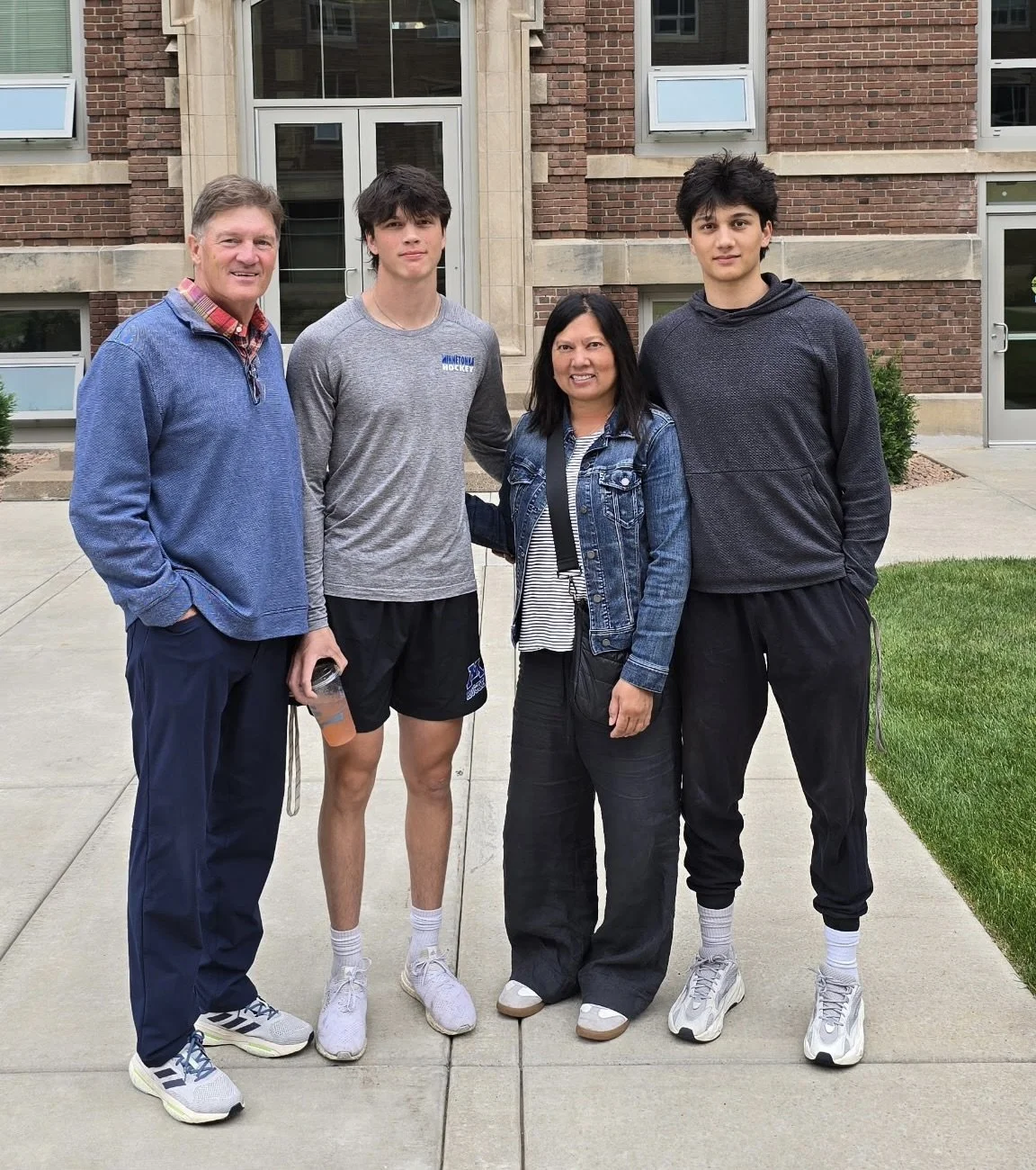 Group of five people standing outside in front of a brick building.