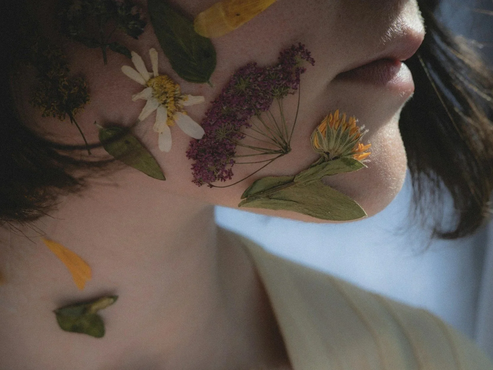 woman with dried flowers on her face and neck.
