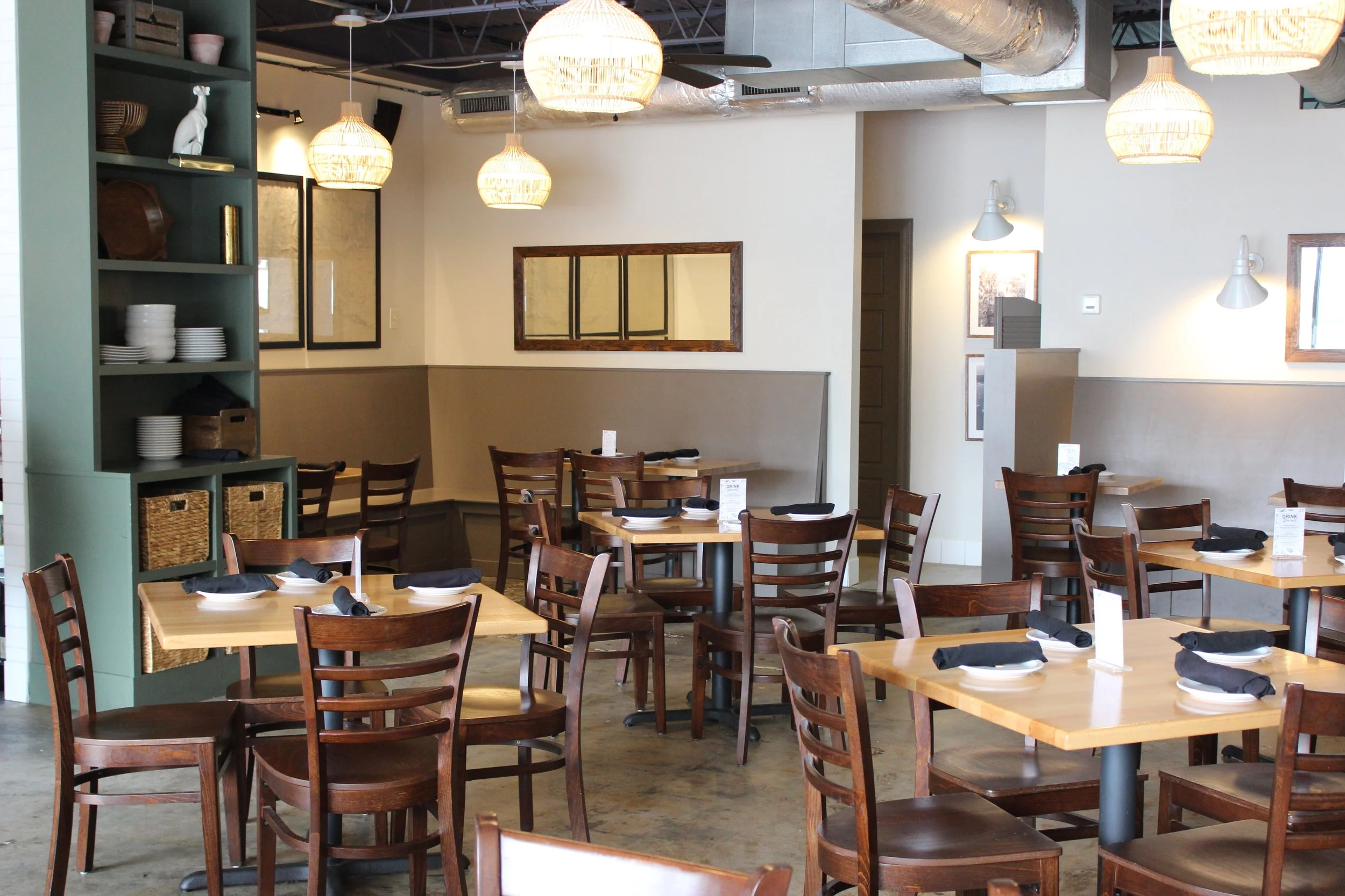 JED’s Local dining room set for a private buyout, with wood tables, black napkins and woven pendant light