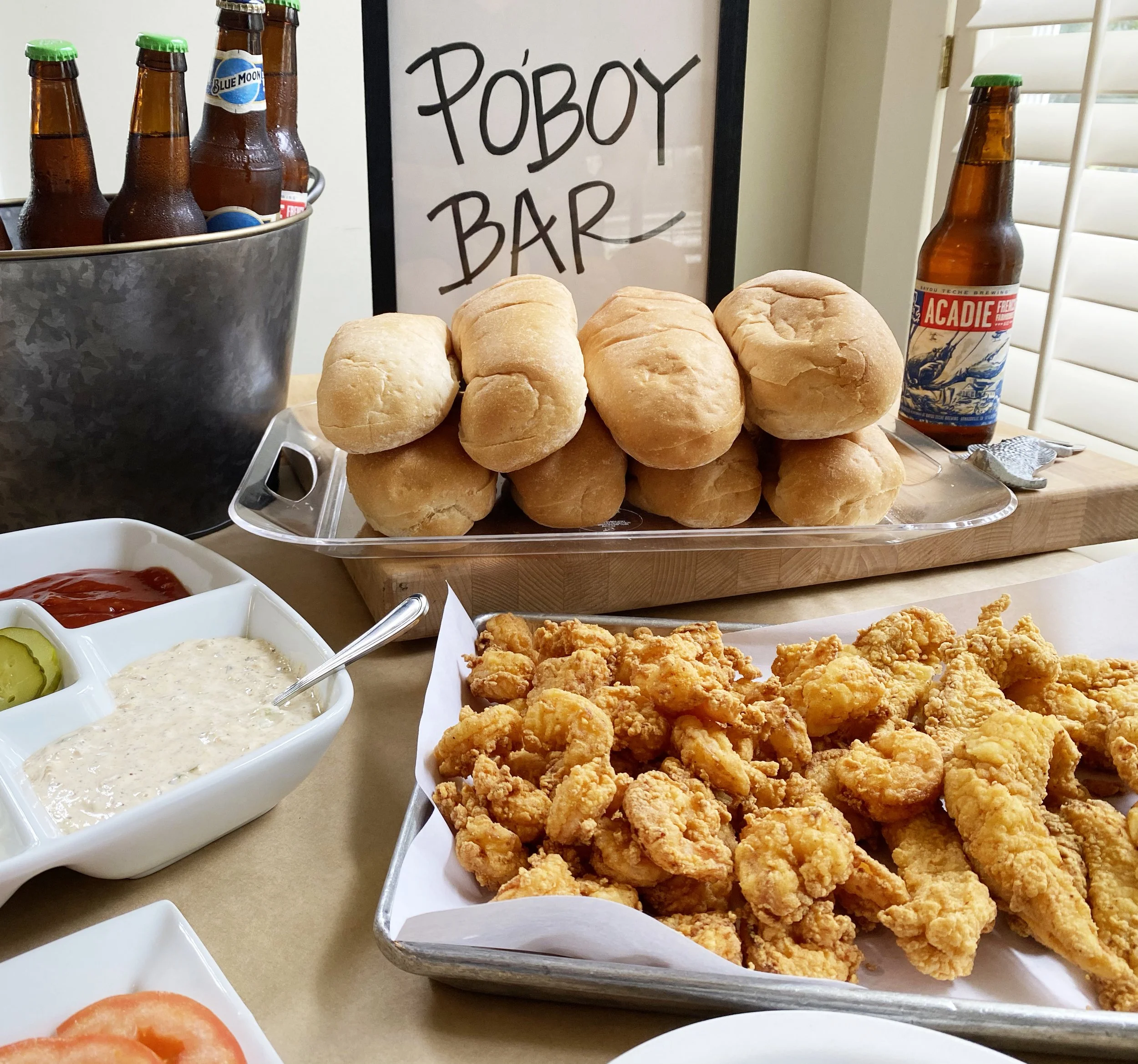Poboy bar setup with fried shrimp, fresh bread, and house-made toppings