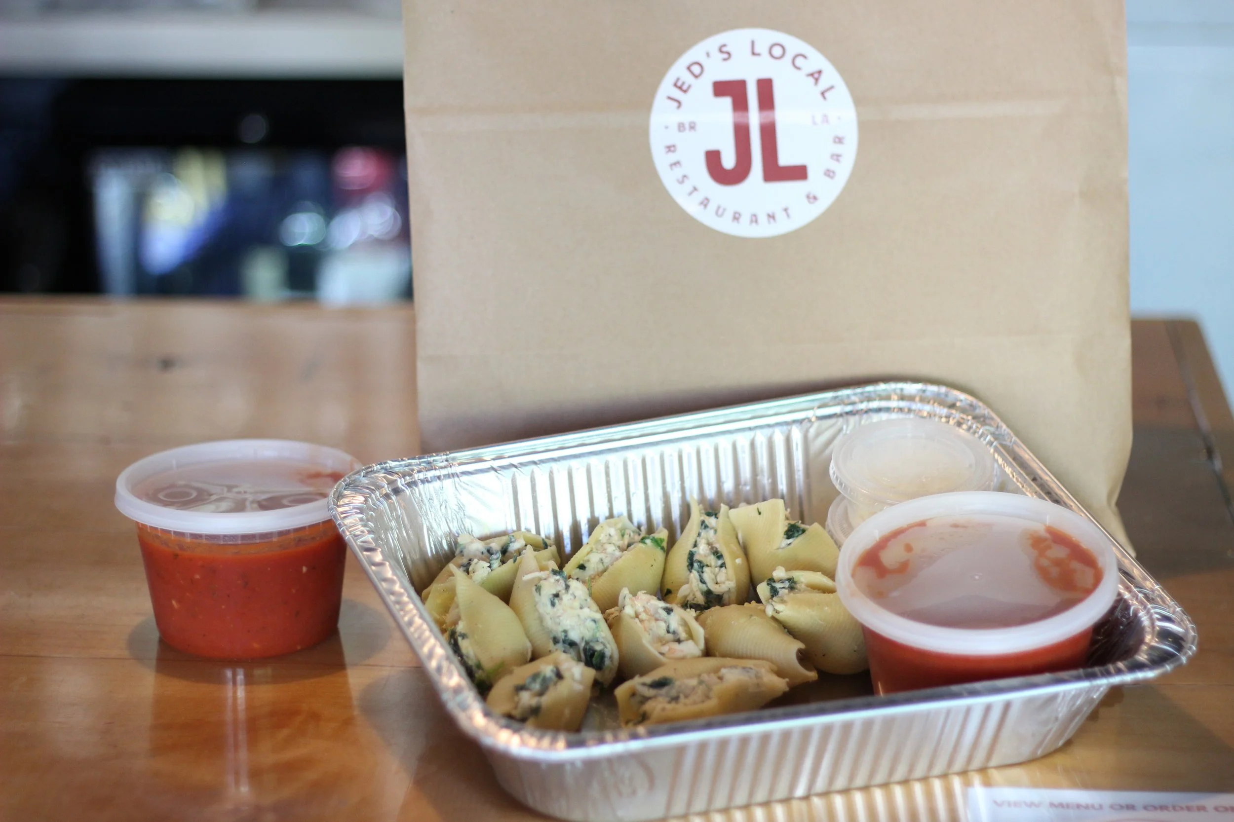 Large food tray prepared by Jed’s Local in Baton Rouge with sauces and branded packaging
