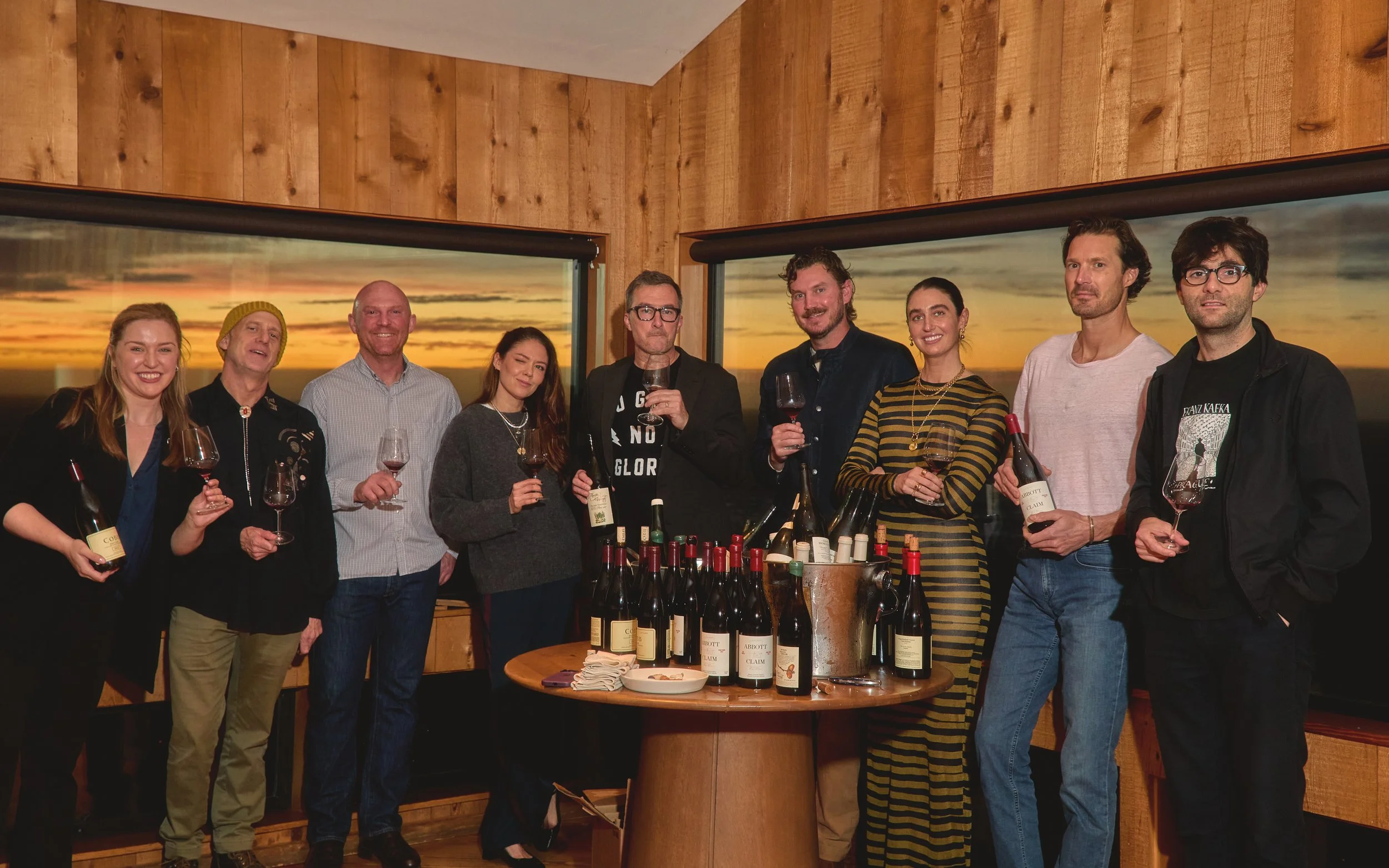 Group of nine people enjoying wine tasting indoors at sunset