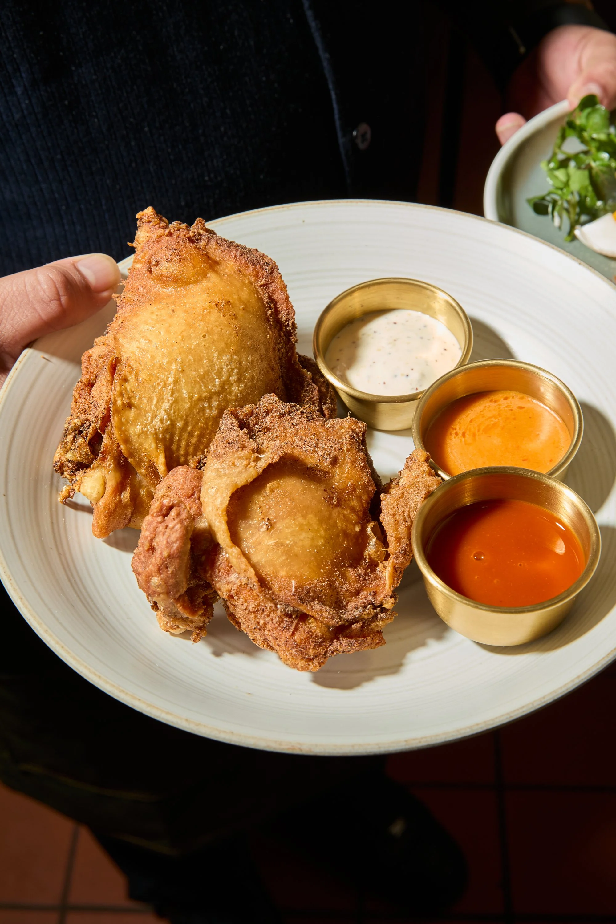 Fried chicken served with three dipping sauces on a white plate
