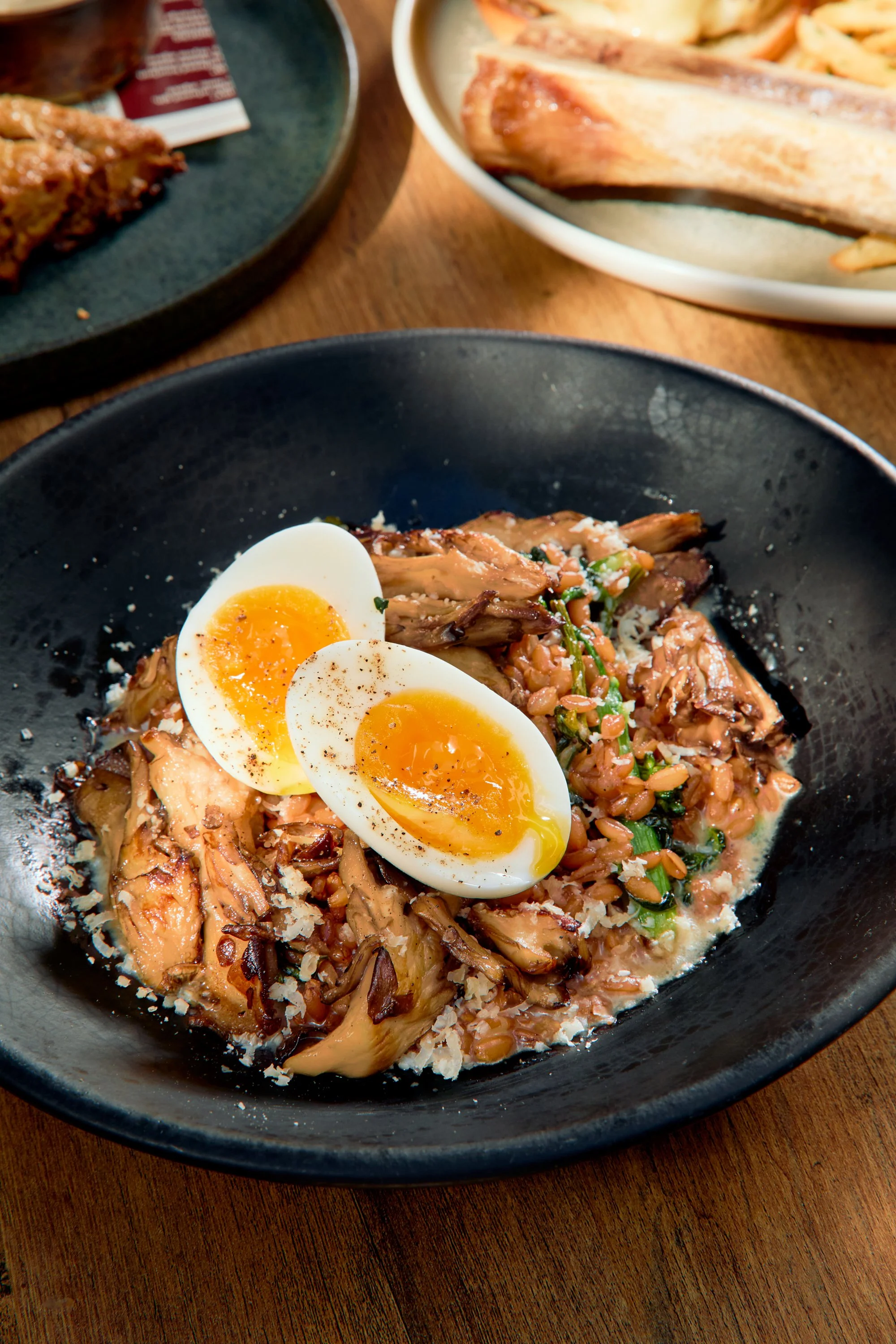 Close-up of a black bowl with halved soft-boiled eggs, shredded chicken, rice, and chopped green onions on top.