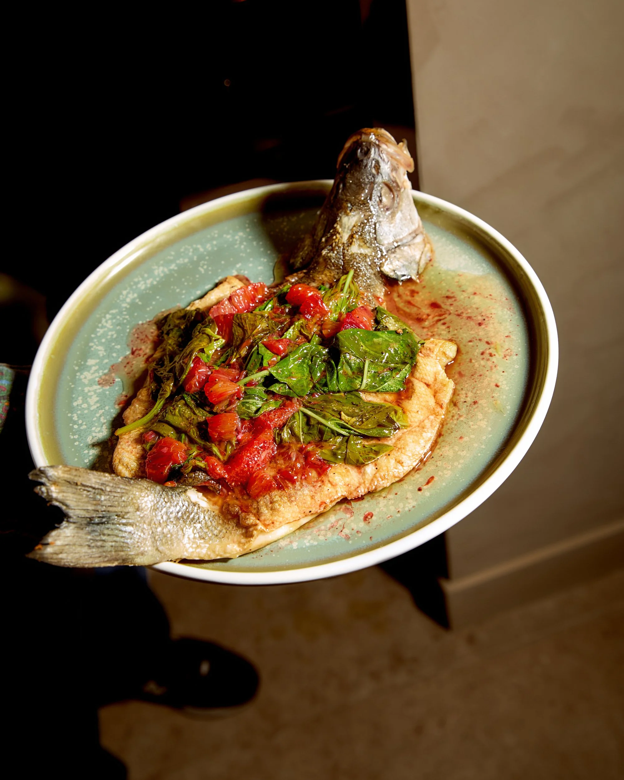 Fish served with vegetables and sauce on a green plate