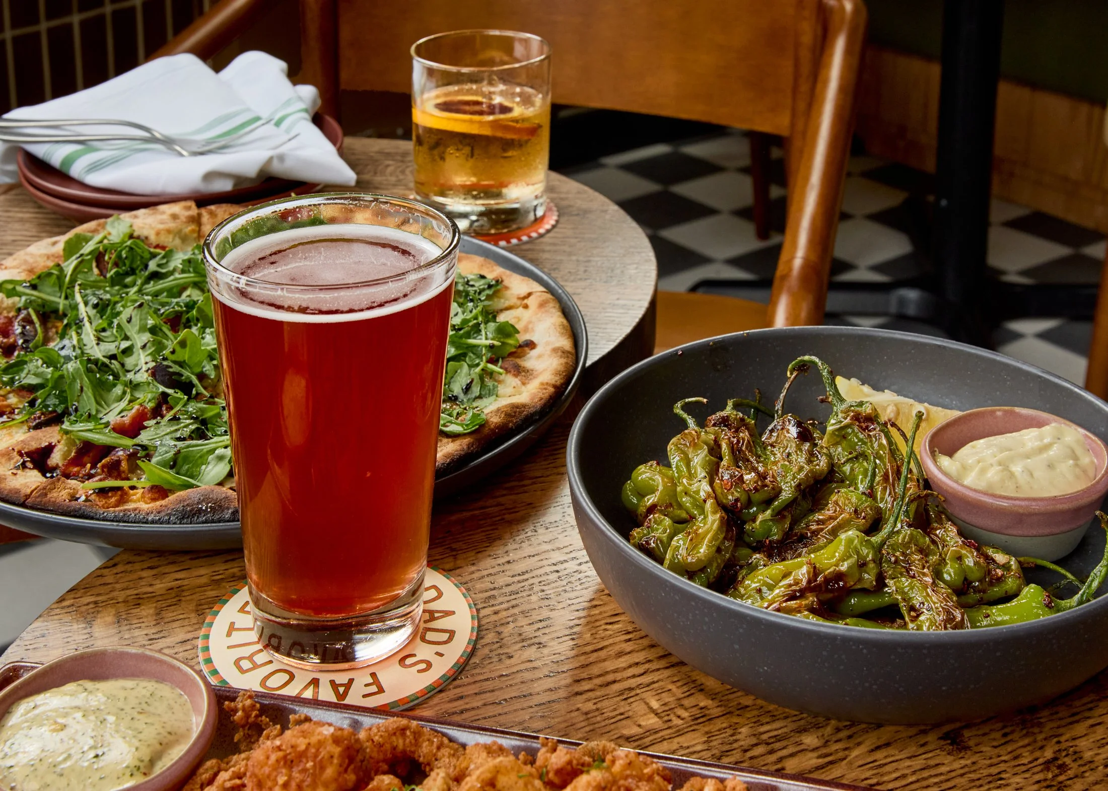 A table with pizza, salads, and beverages in a restaurant setting.