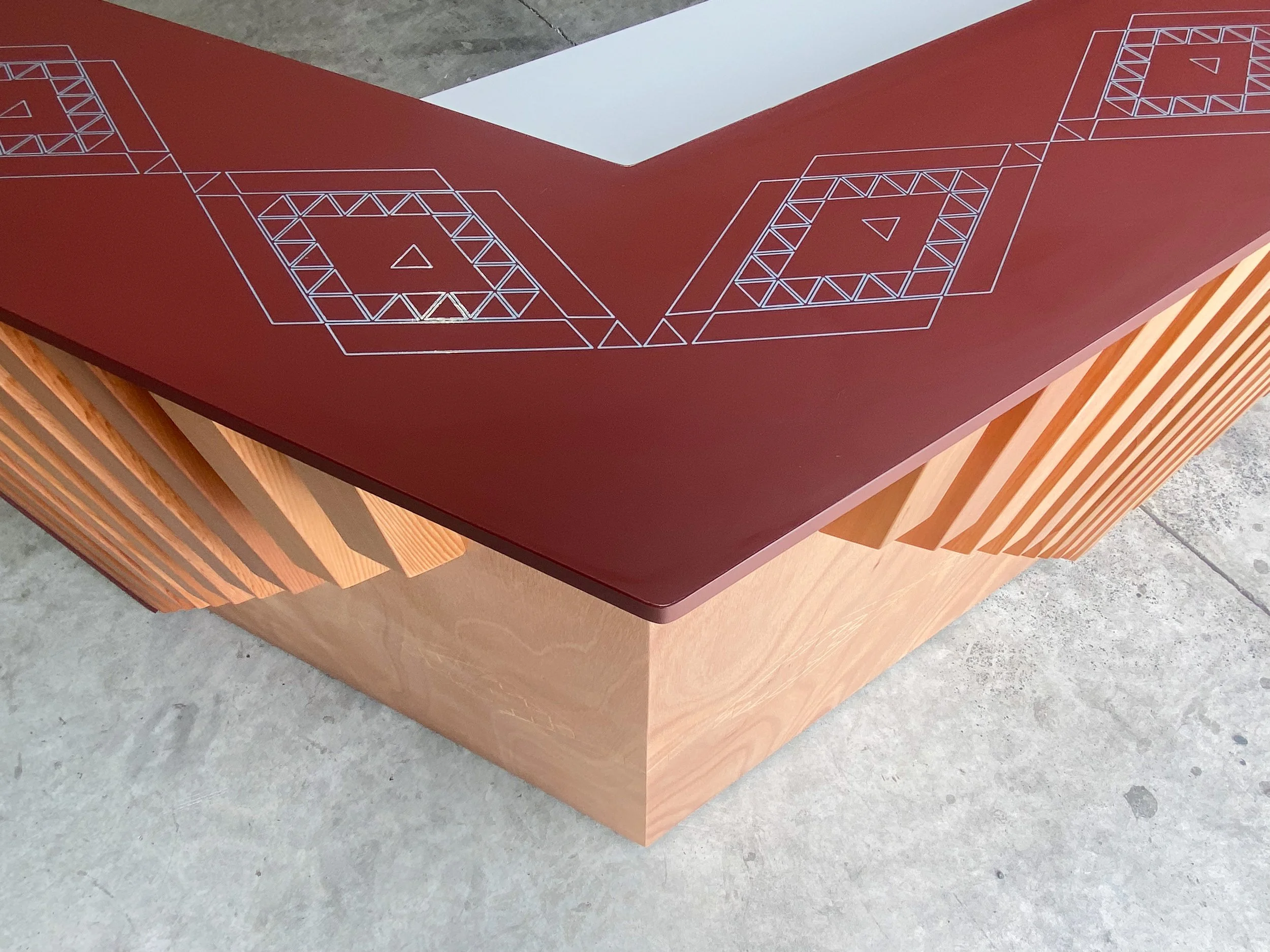 A wooden table with a red top featuring geometric line art designs on its surface.