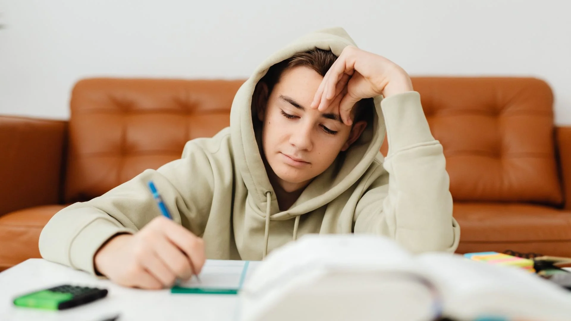 Young man focused on studying at a desk in his home office using a laptop.