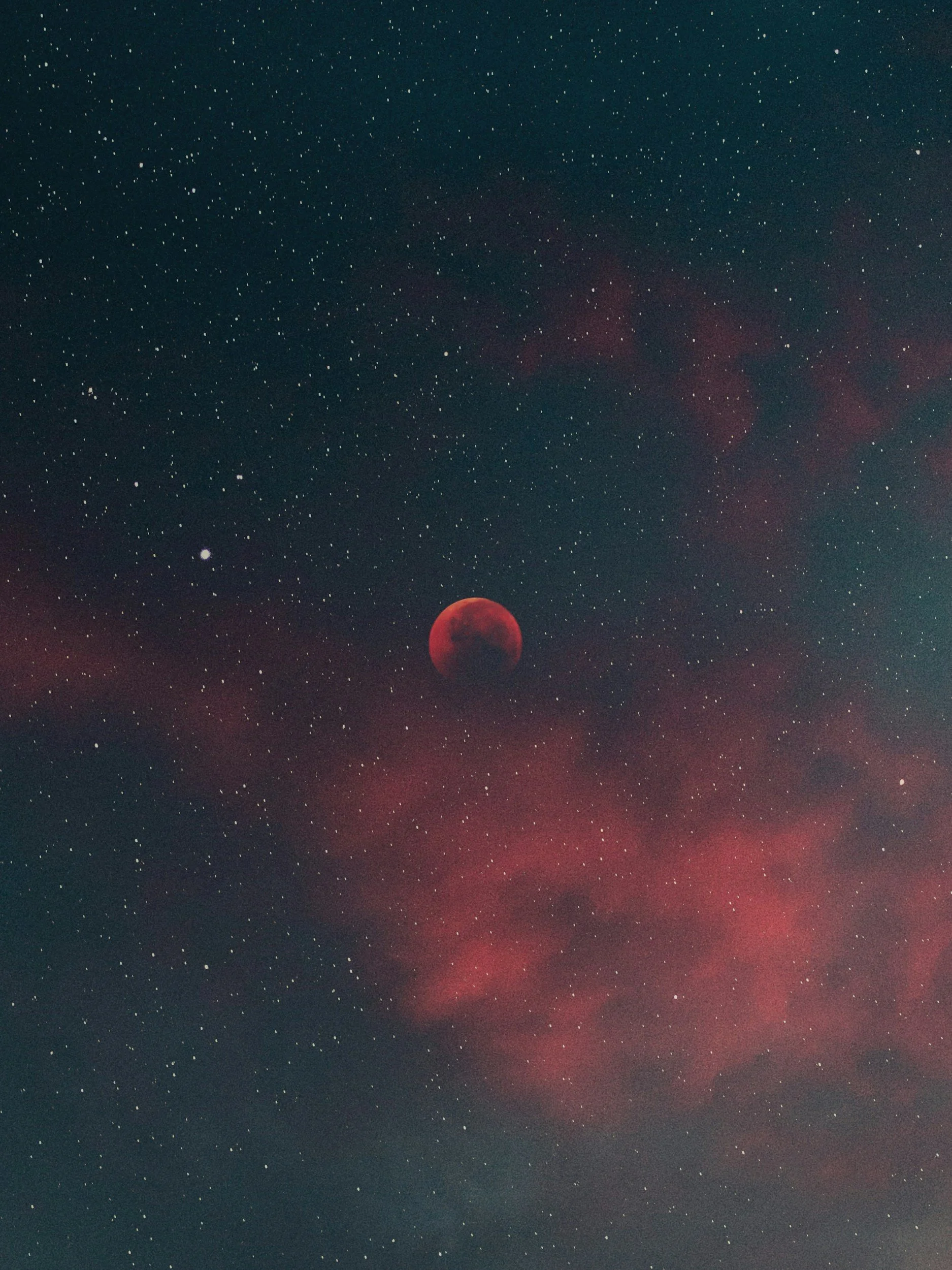 Night sky with numerous stars, a red moon, and reddish clouds.