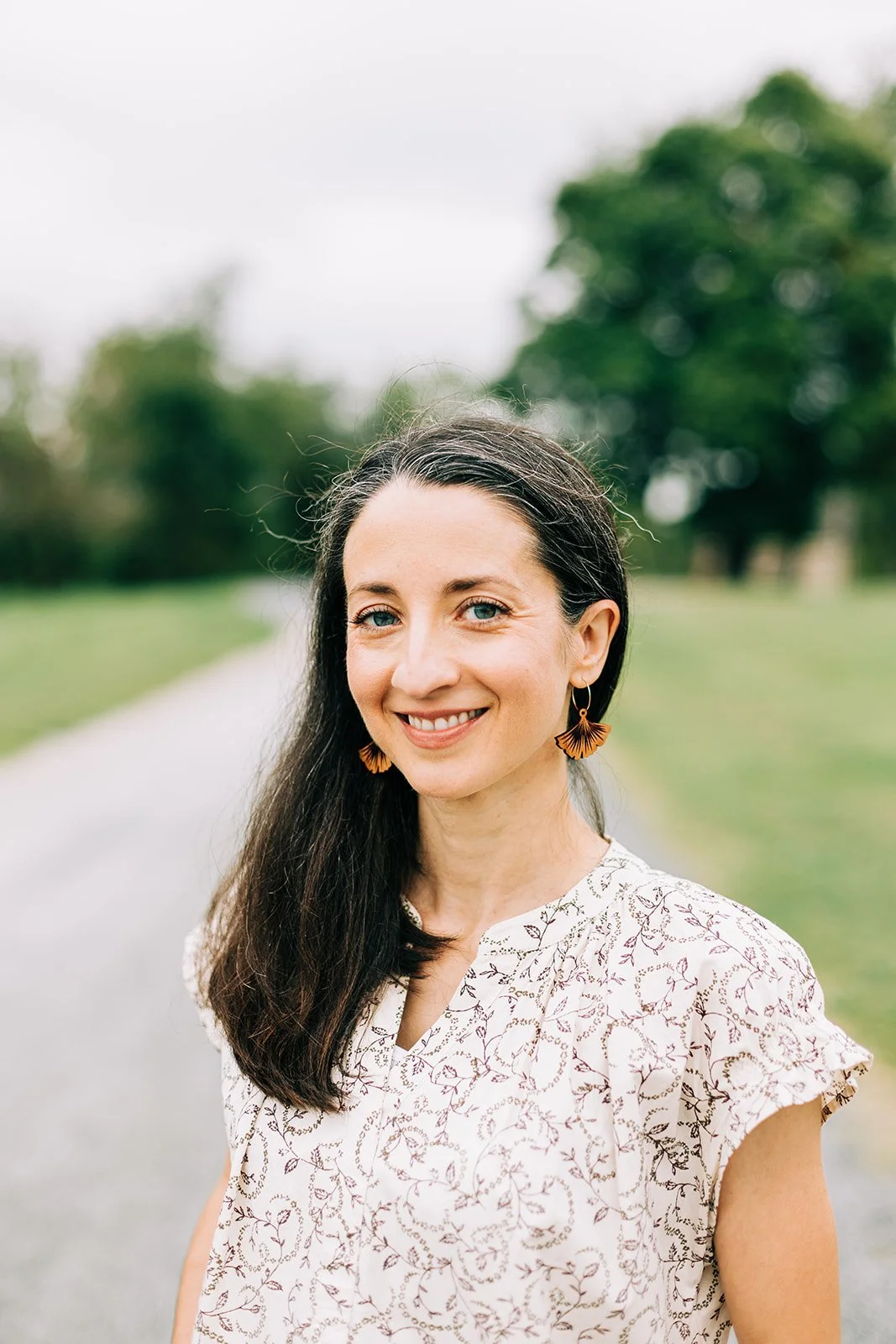 Headshot of Ronna standing in front of a gravel road outside