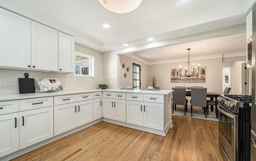 Kitchen with light hardwood floors, fresh white painted cabinets and dark brown dining room table